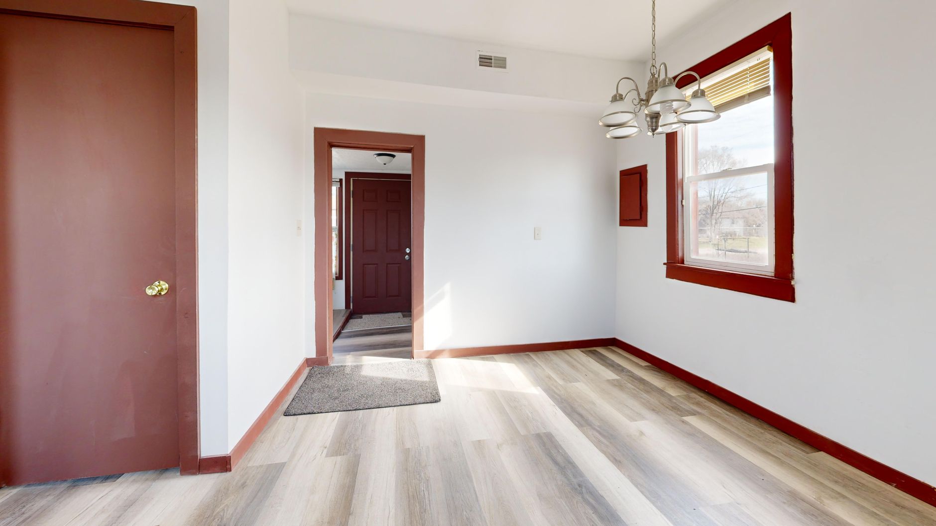 Spacious empty room with modern flooring and natural light through a large window, ideal for real estate listings.