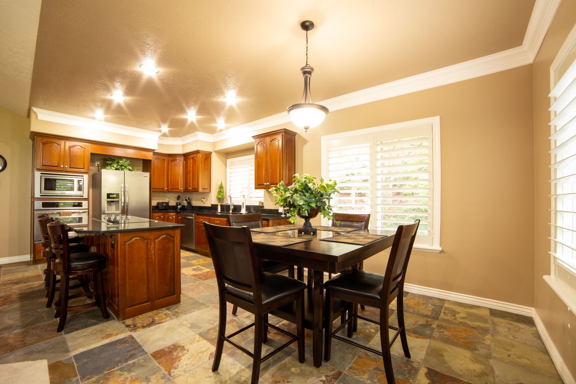 A beautifully lit kitchen and dining area with wooden furniture and modern appliances.