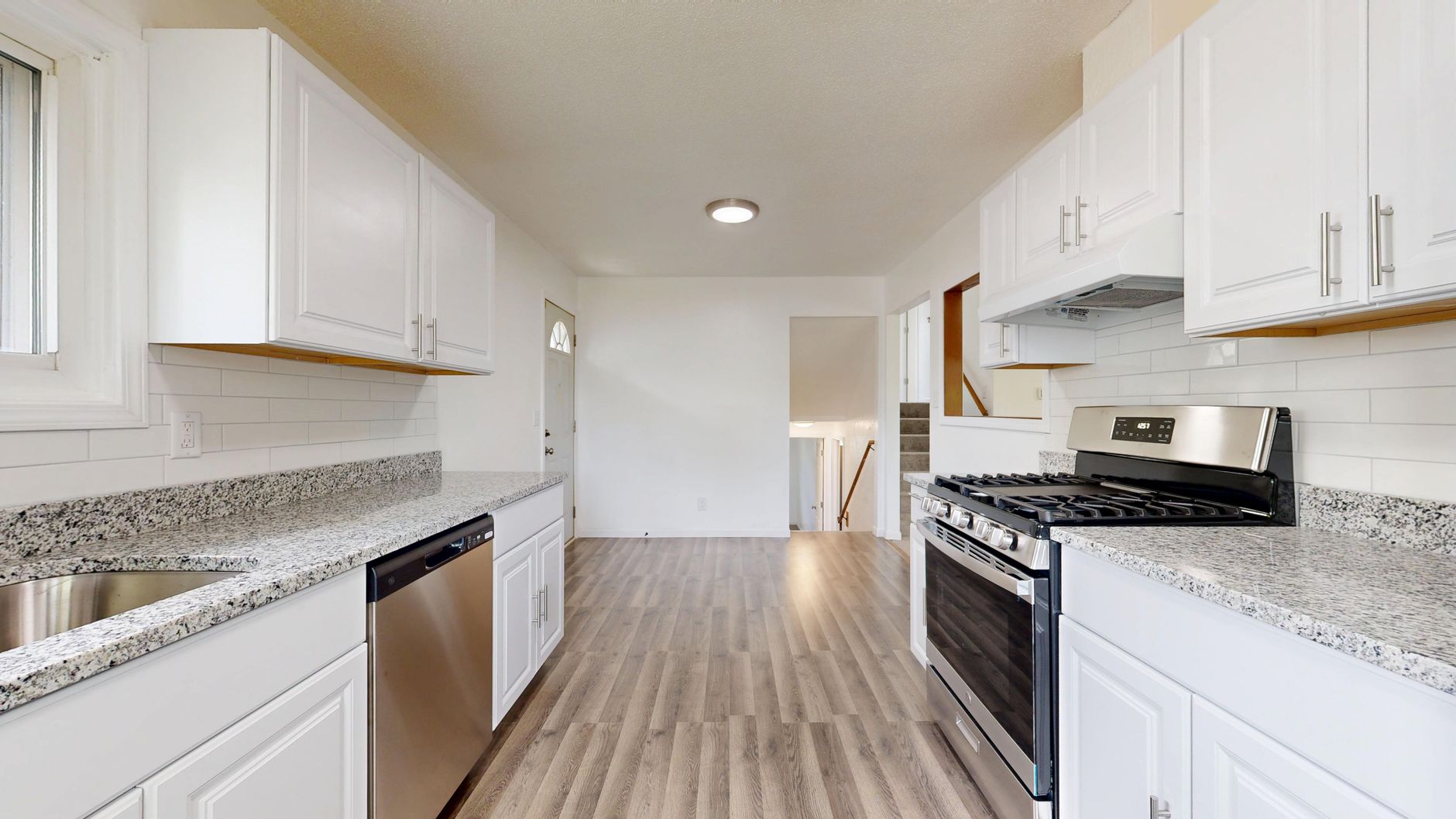 Spacious kitchen with white cabinets, granite countertops, and stainless steel appliances.