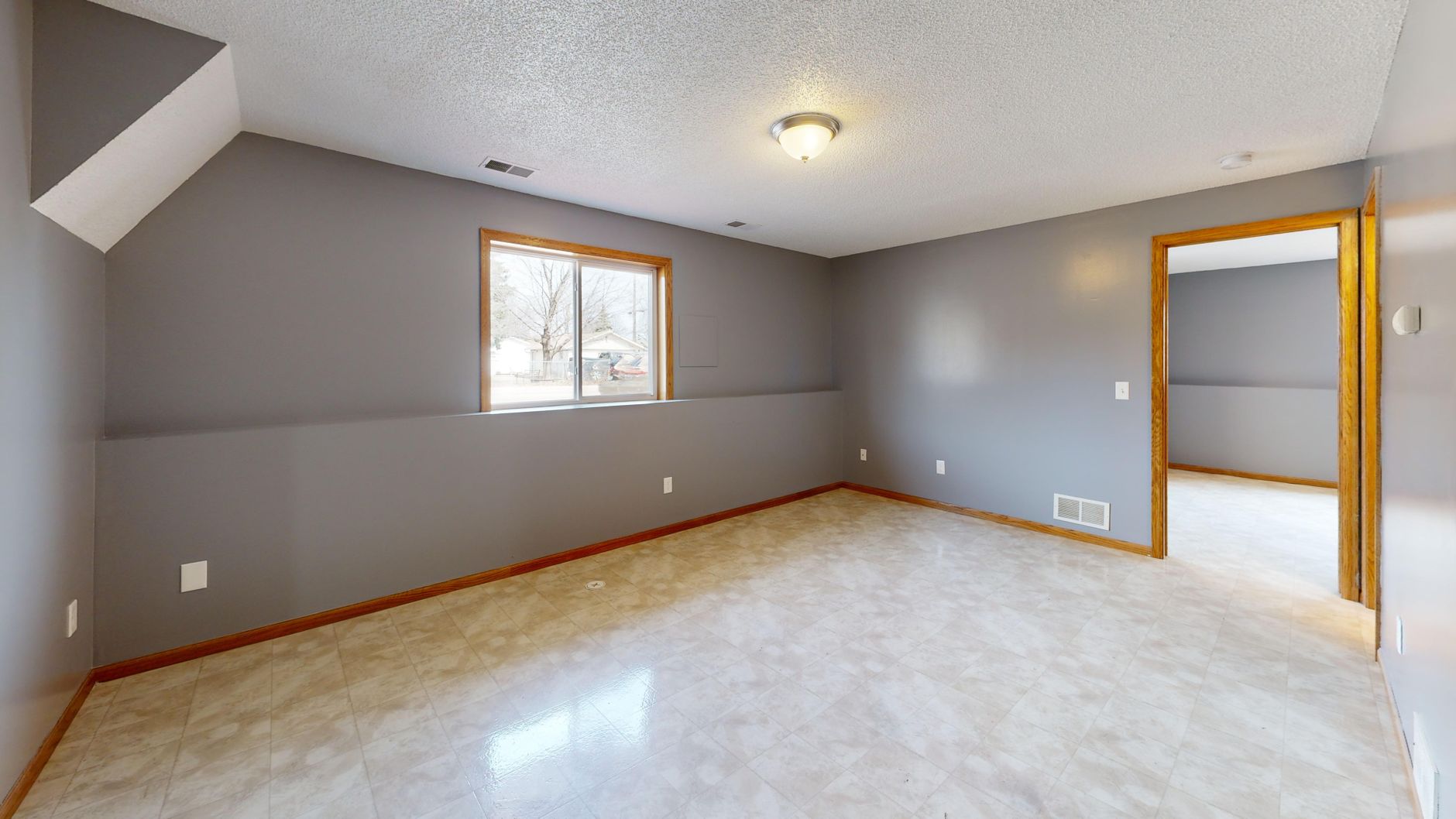 Spacious empty room with natural light through window, ideal for real estate listings.