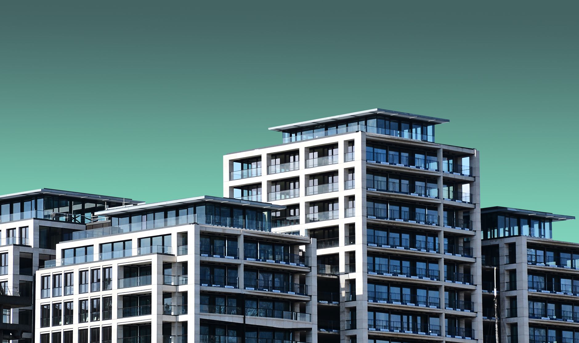 Contemporary apartment buildings with a minimalist design are set against a clear blue sky.