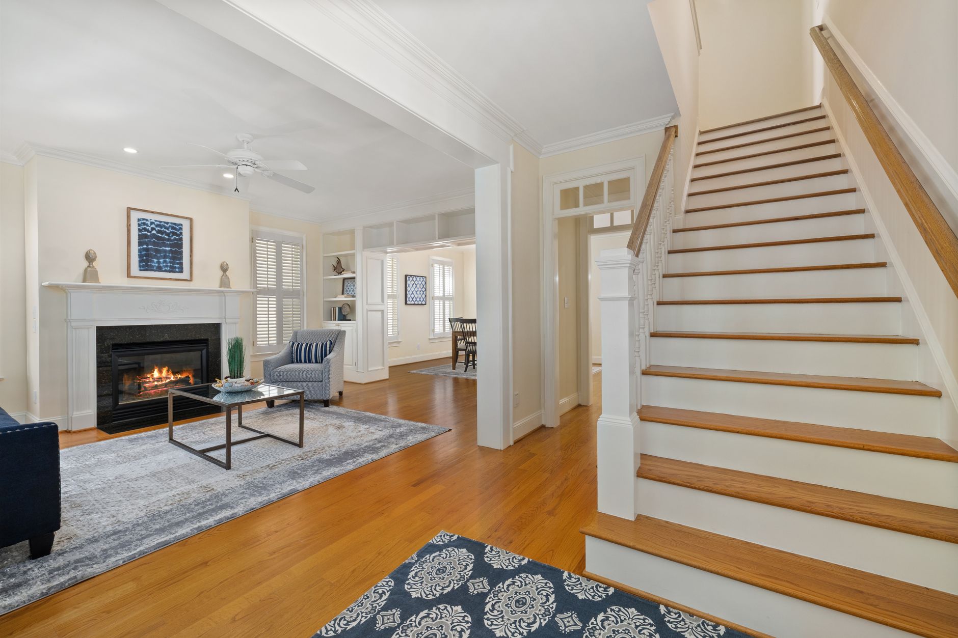 A modern living room featuring a cozy fireplace and elegant decor with a view of the dining area.