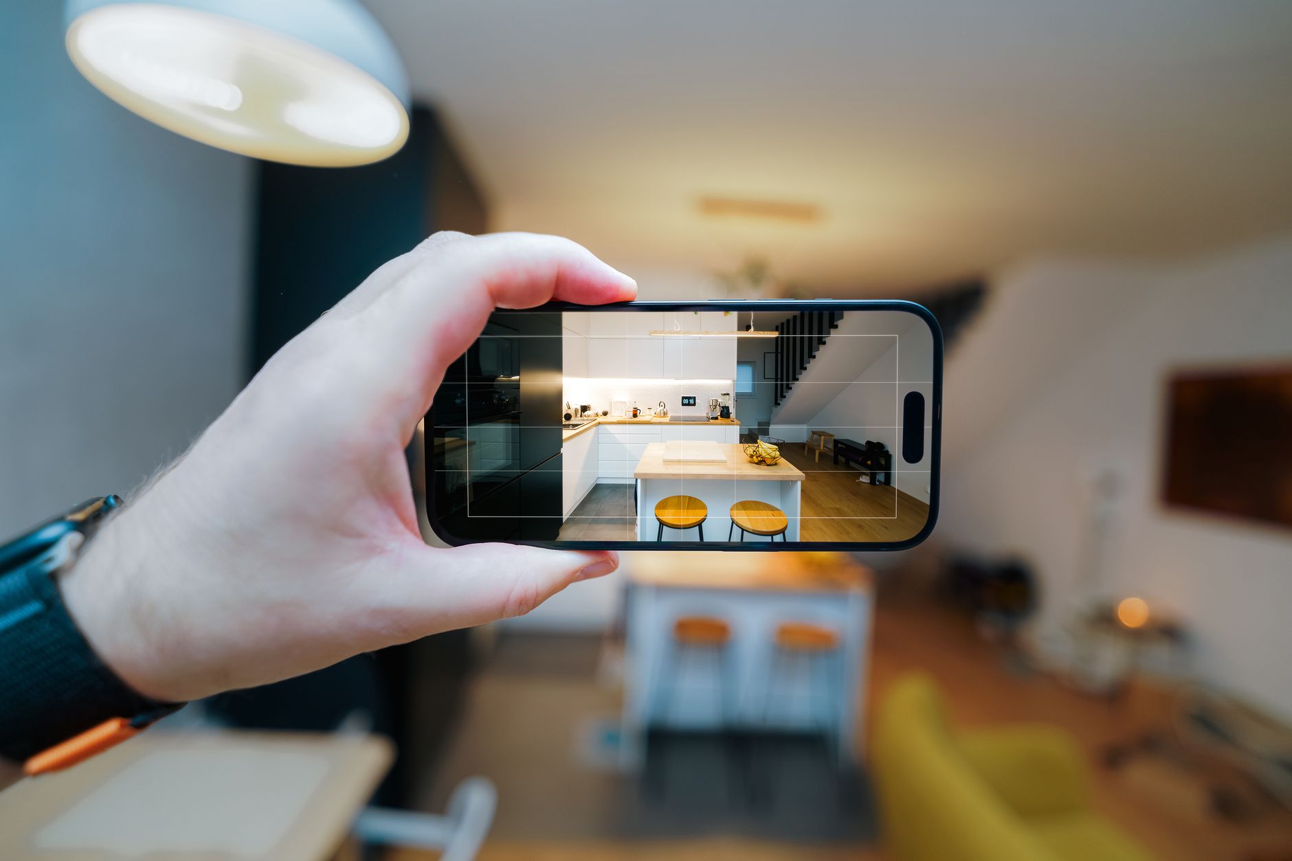 A smartphone in focus capturing a modern kitchen interior, showcasing real estate potential.
