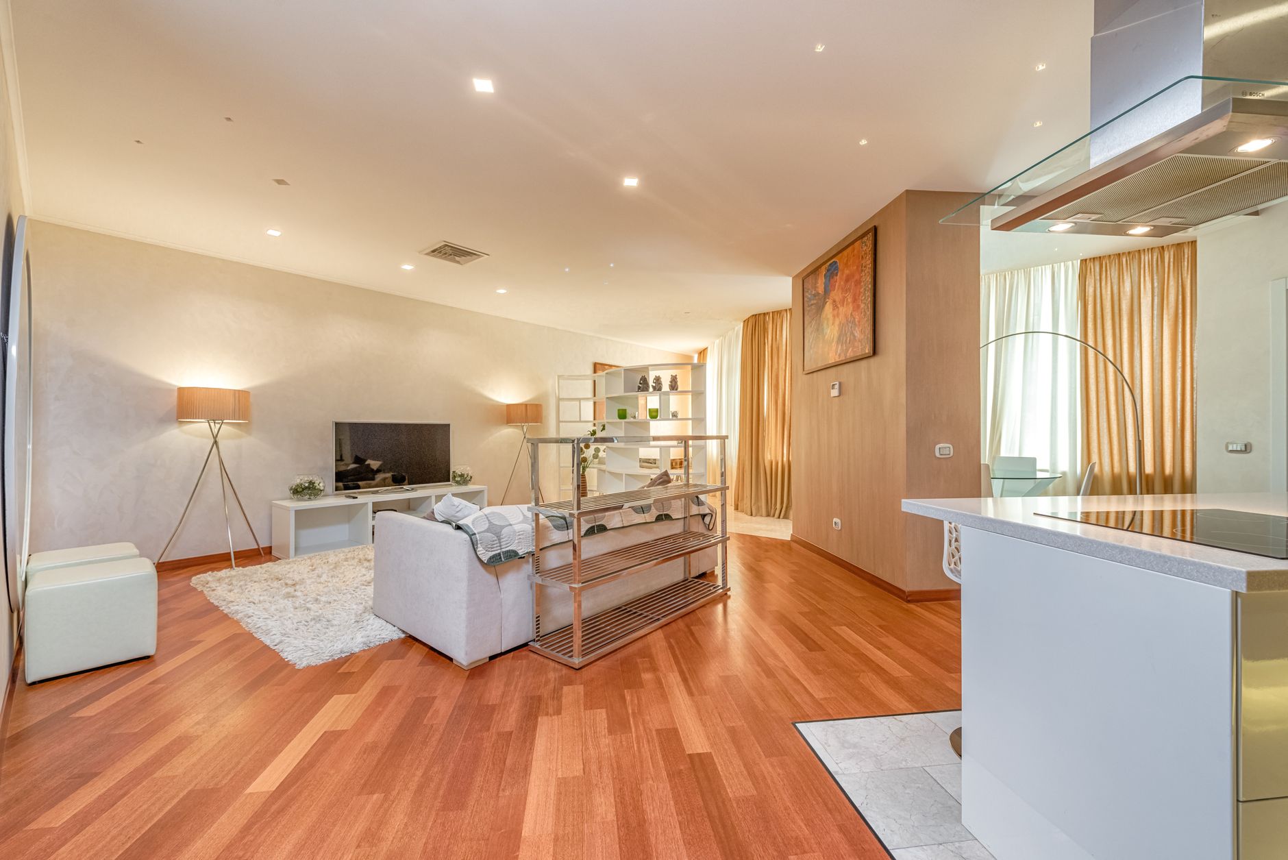 Interior of spacious living room with parquet floor and sofa placed in front of TV in modern apartment with suspended ceiling and
