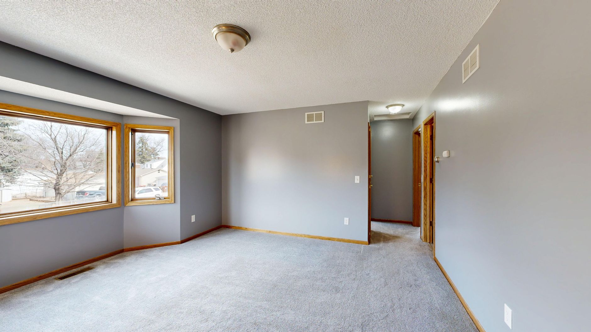 Spacious empty room with gray walls and large windows offering natural light.
