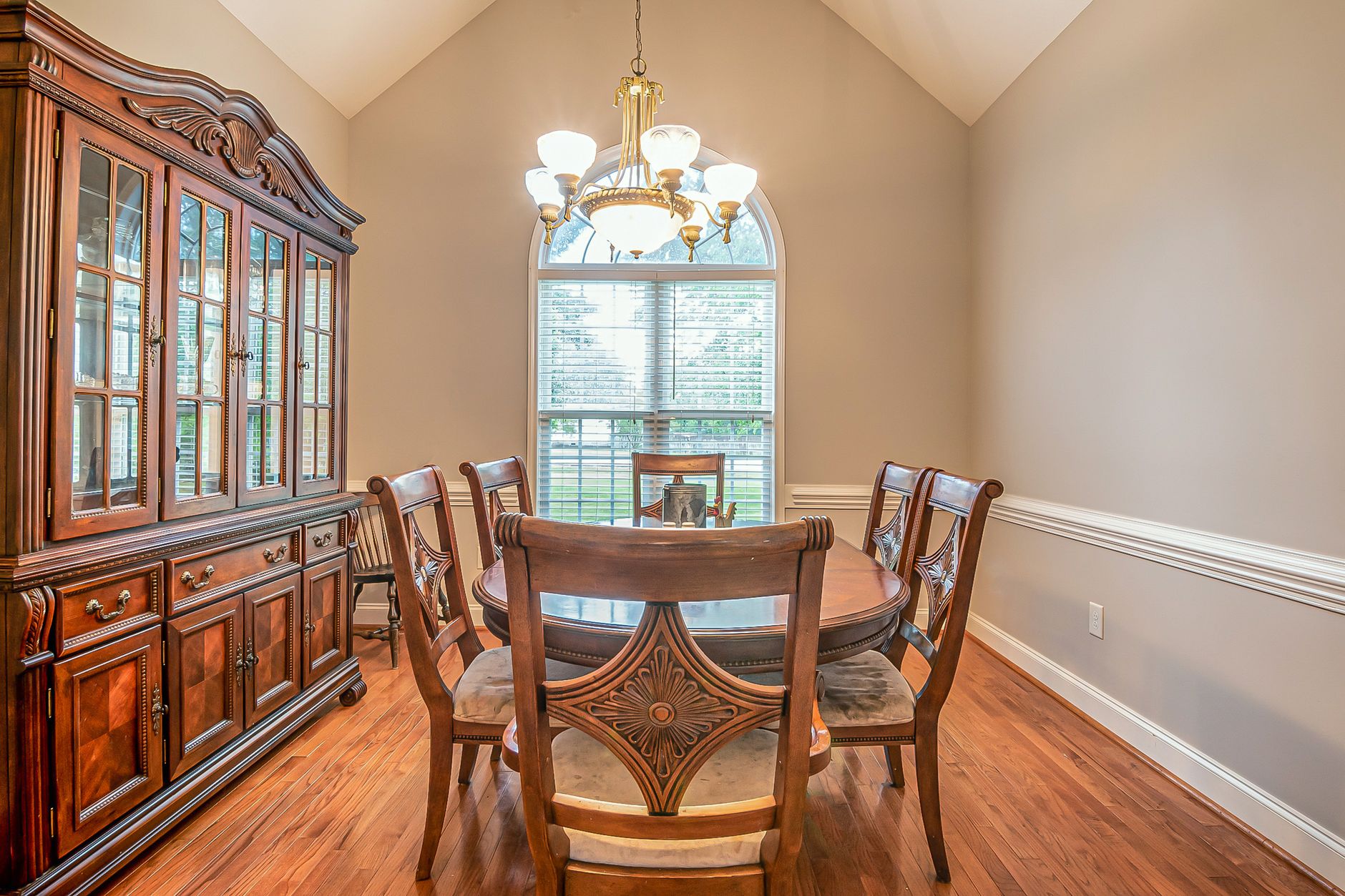 Spacious dining room showcasing a classic wooden cabinet and dining set under elegant lighting.
