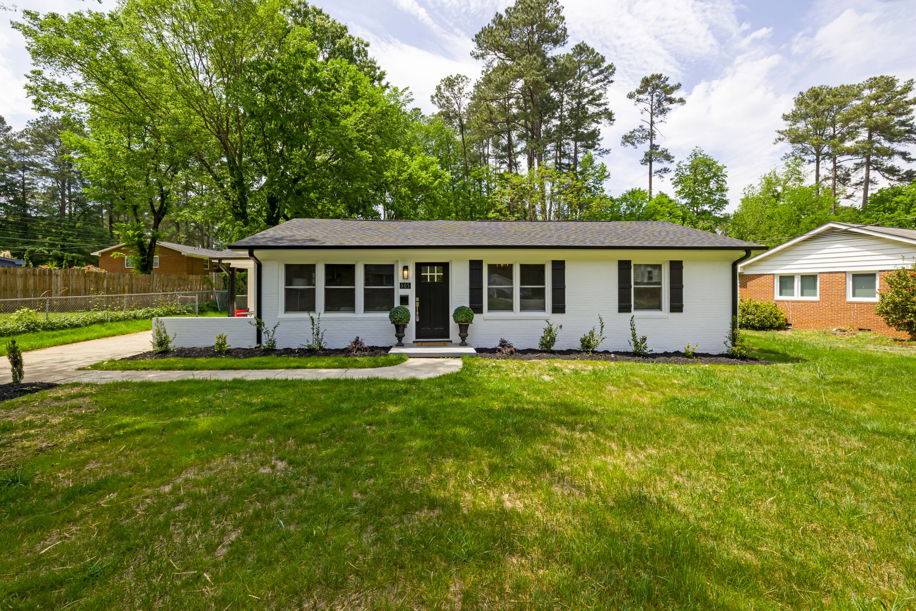 Beautiful single-story suburban house with a front lawn and surrounding trees.
