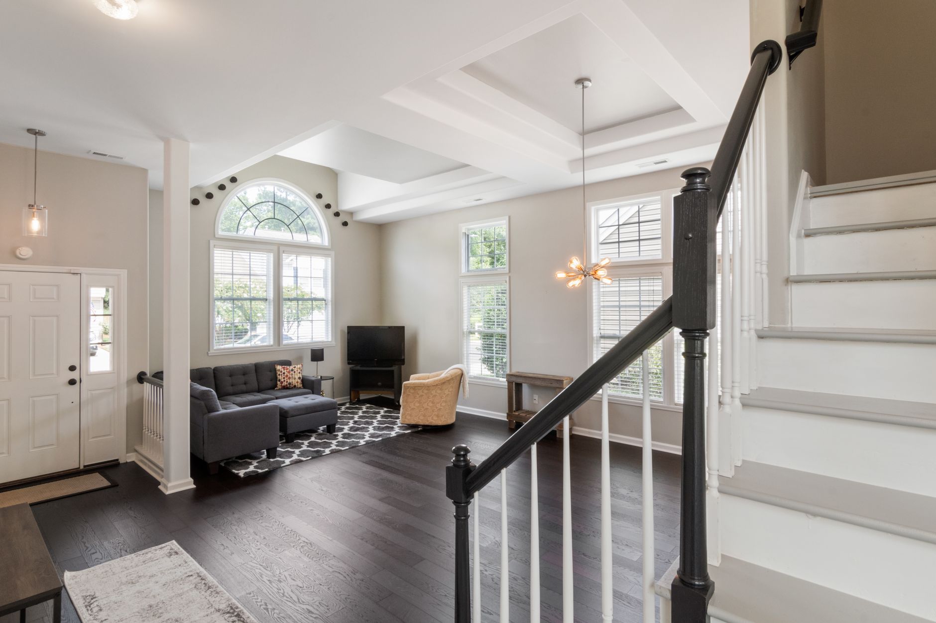 Bright and spacious contemporary living room with elegant staircase and modern furniture.