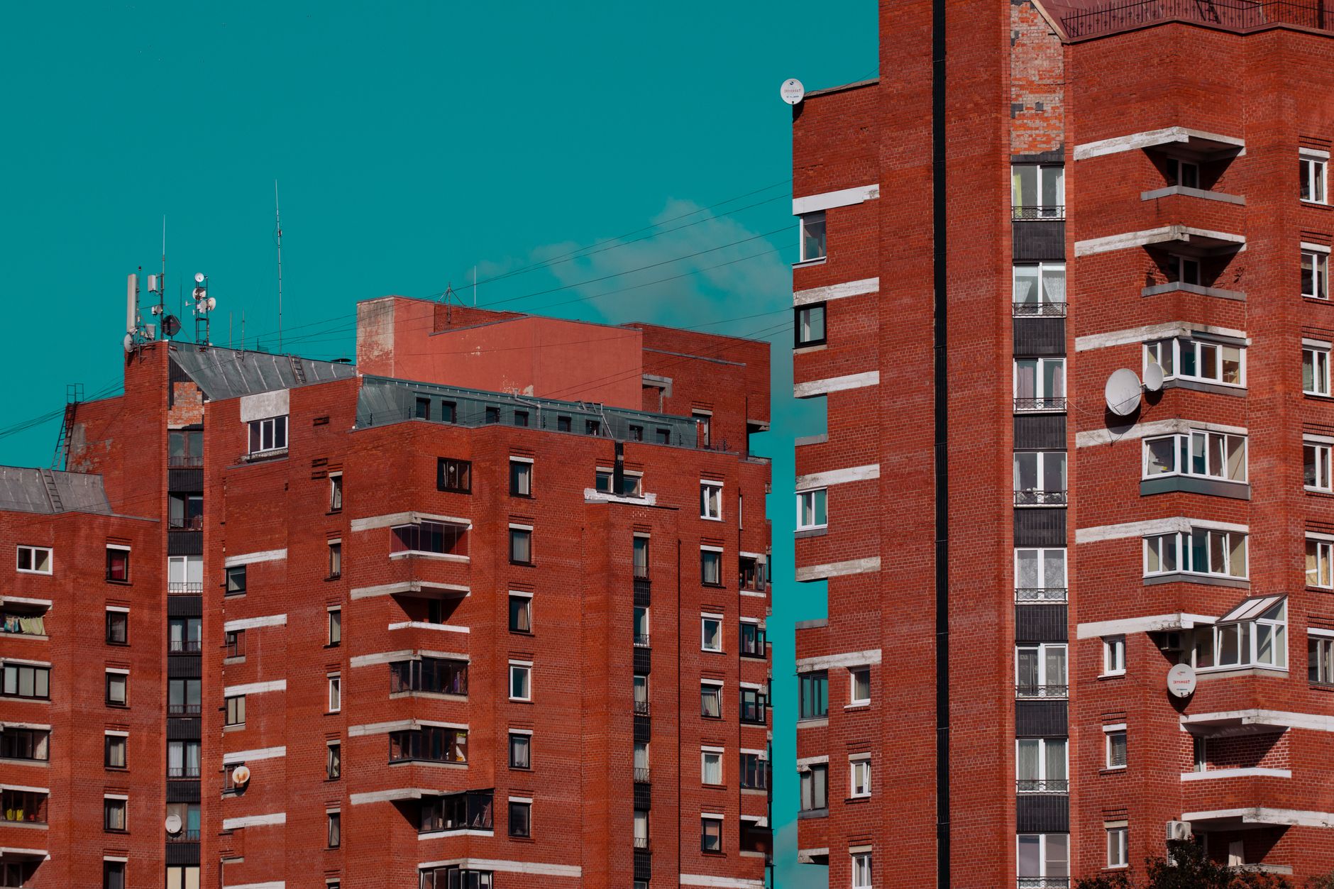 Red brick apartment buildings in Pārdaugava, Riga under a clear turquoise sky.