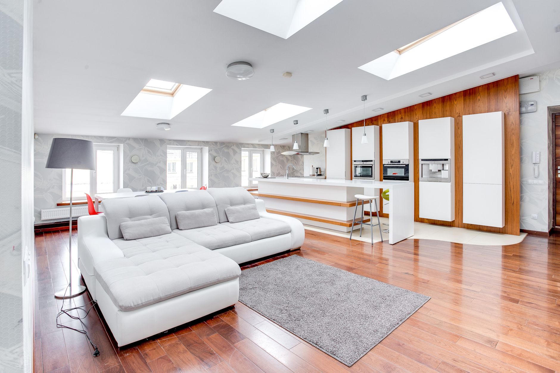 Bright open-plan living room with modern kitchen and skylights.