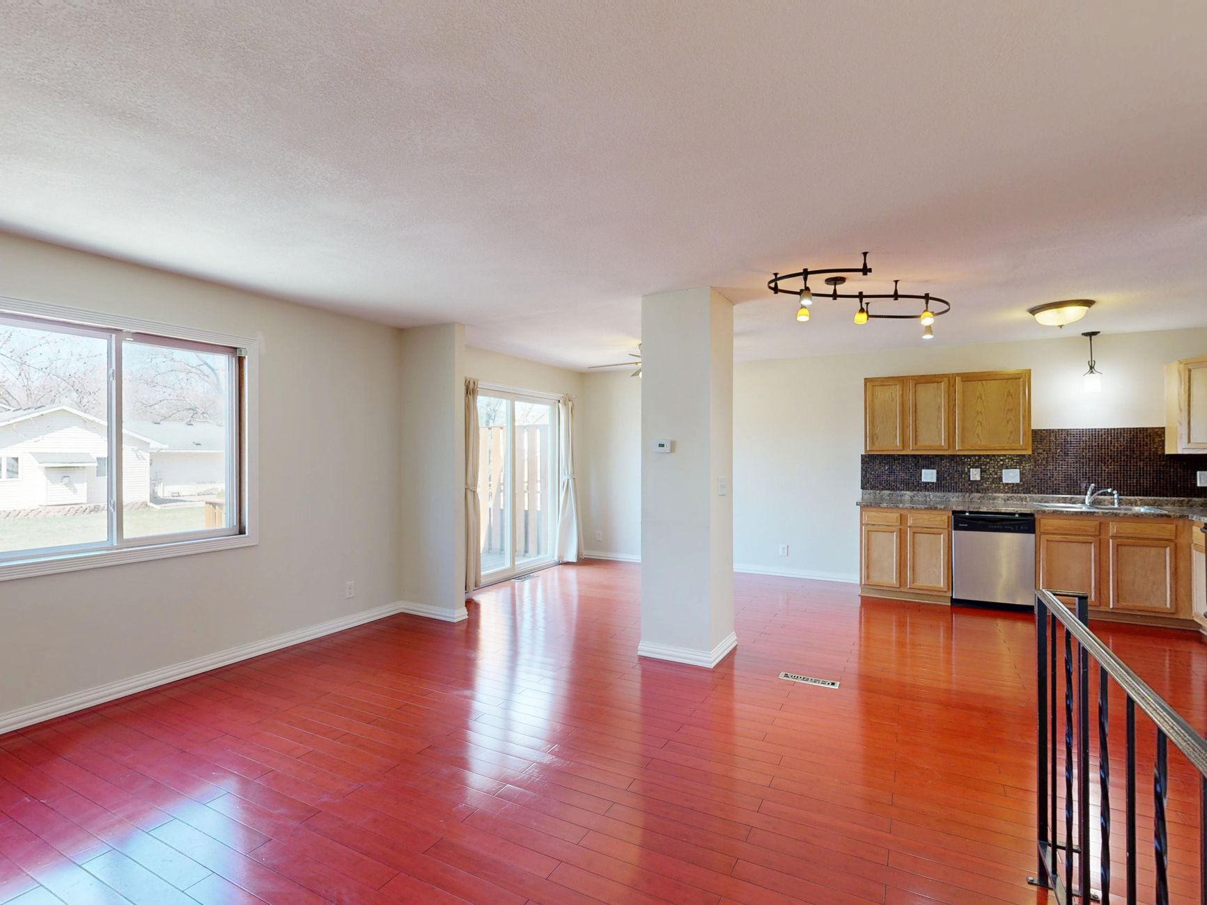 Spacious empty kitchen with hardwood floors and natural light.
