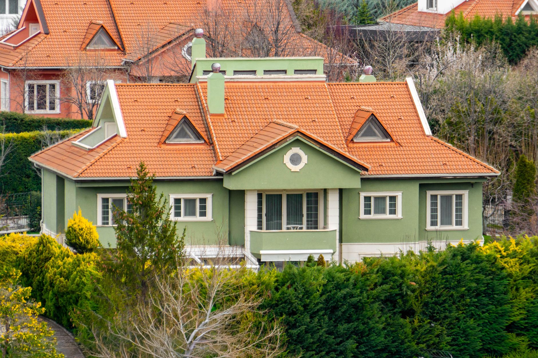 A picturesque green house with an orange roof surrounded by greenery in Ankara, Türkiye.