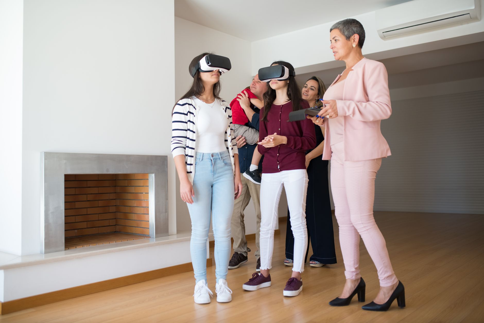 Family experiencing virtual reality house tour guided by a realtor indoors.