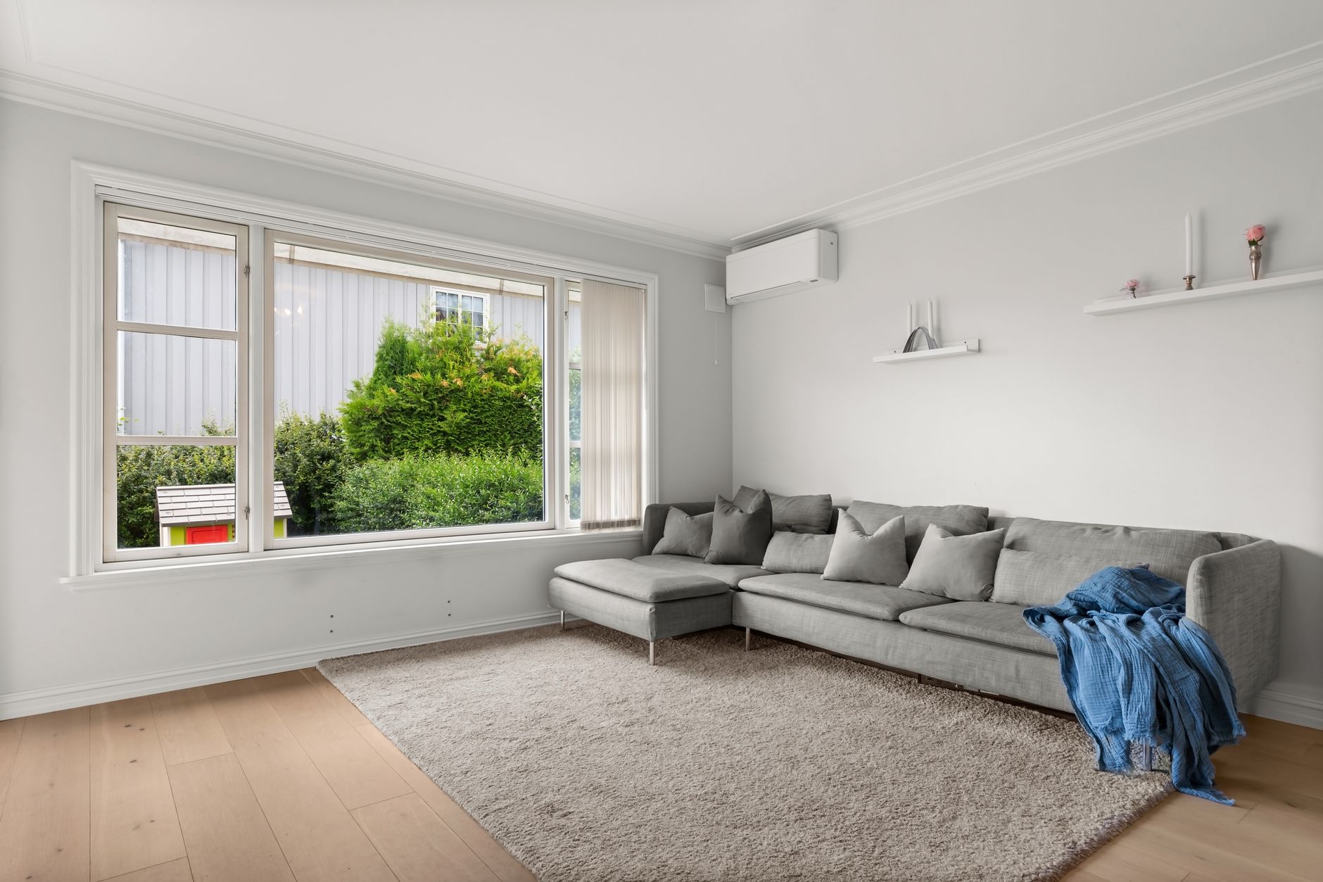 Elegant living room with a grey sofa, large windows, and neutral decor accents.