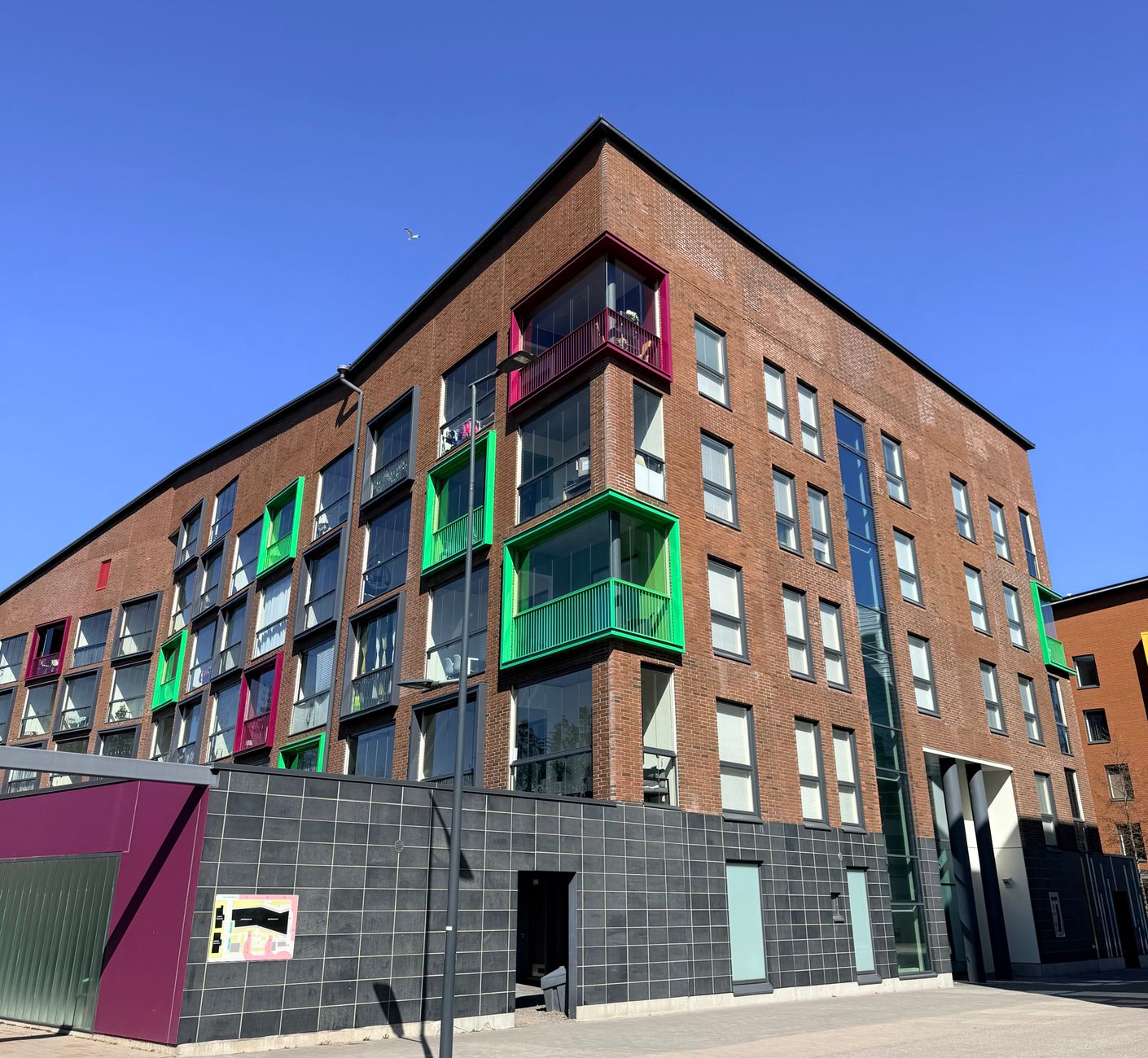 A vibrant modern apartment complex with colorful balconies in Vantaa, Finland under a clear blue sky.