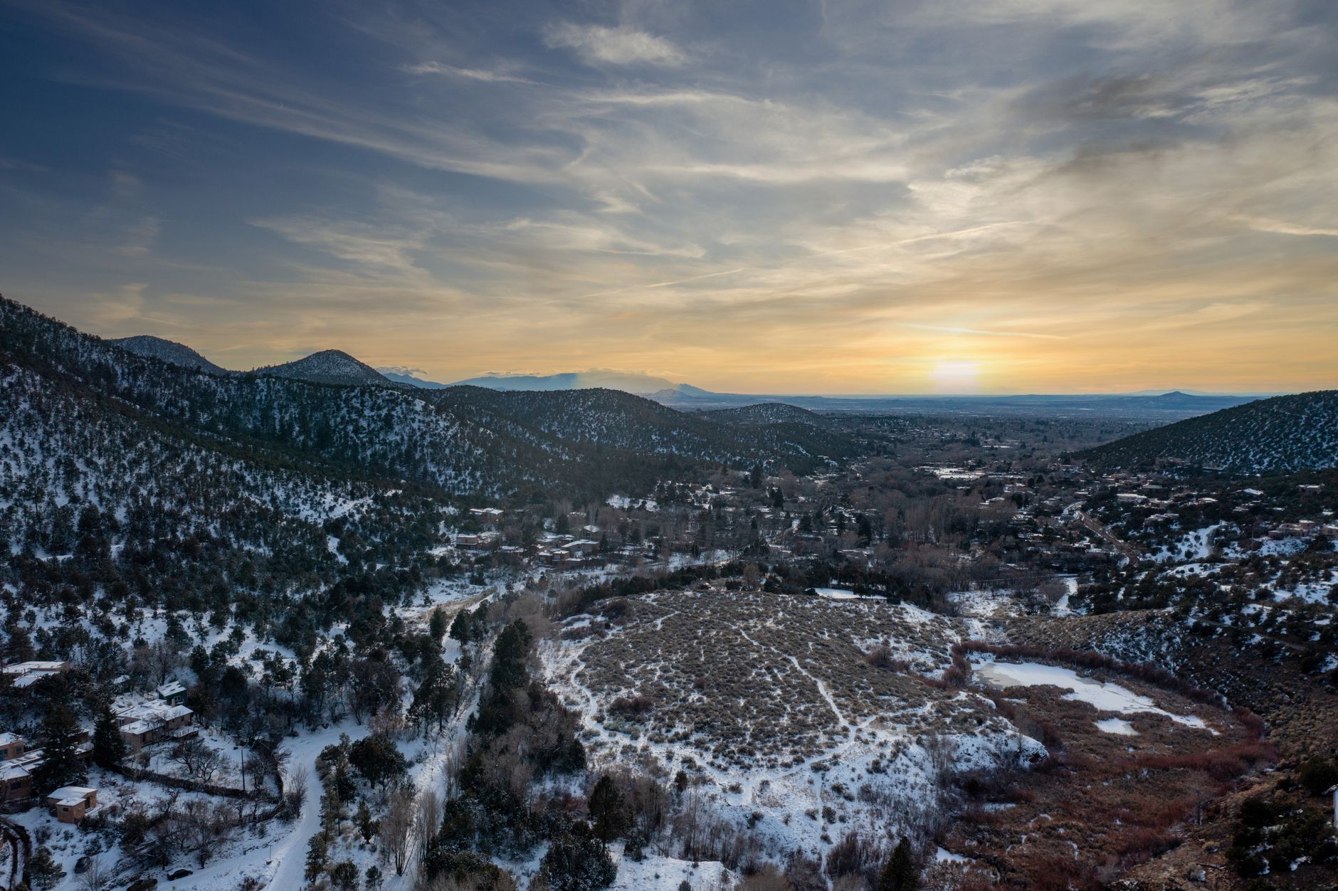 A breathtaking aerial view of Santa Fe's snowy landscape at sunset, showcasing nature's beauty.