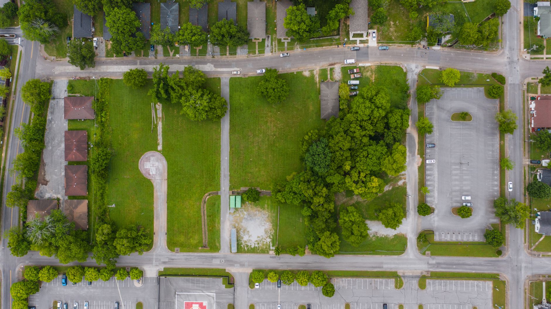 Top view of parked vehicles, parking lots, and green spaces in a residential area.