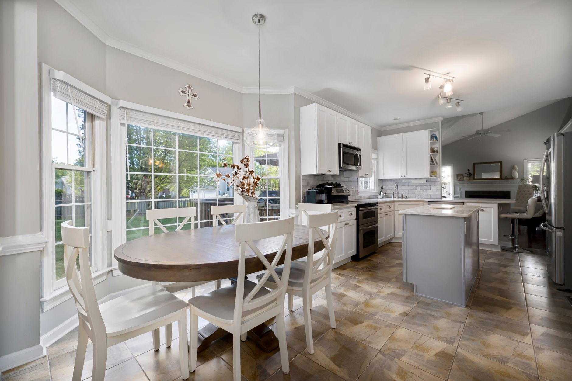 Bright and spacious kitchen with dining area, white cabinets, and natural light.