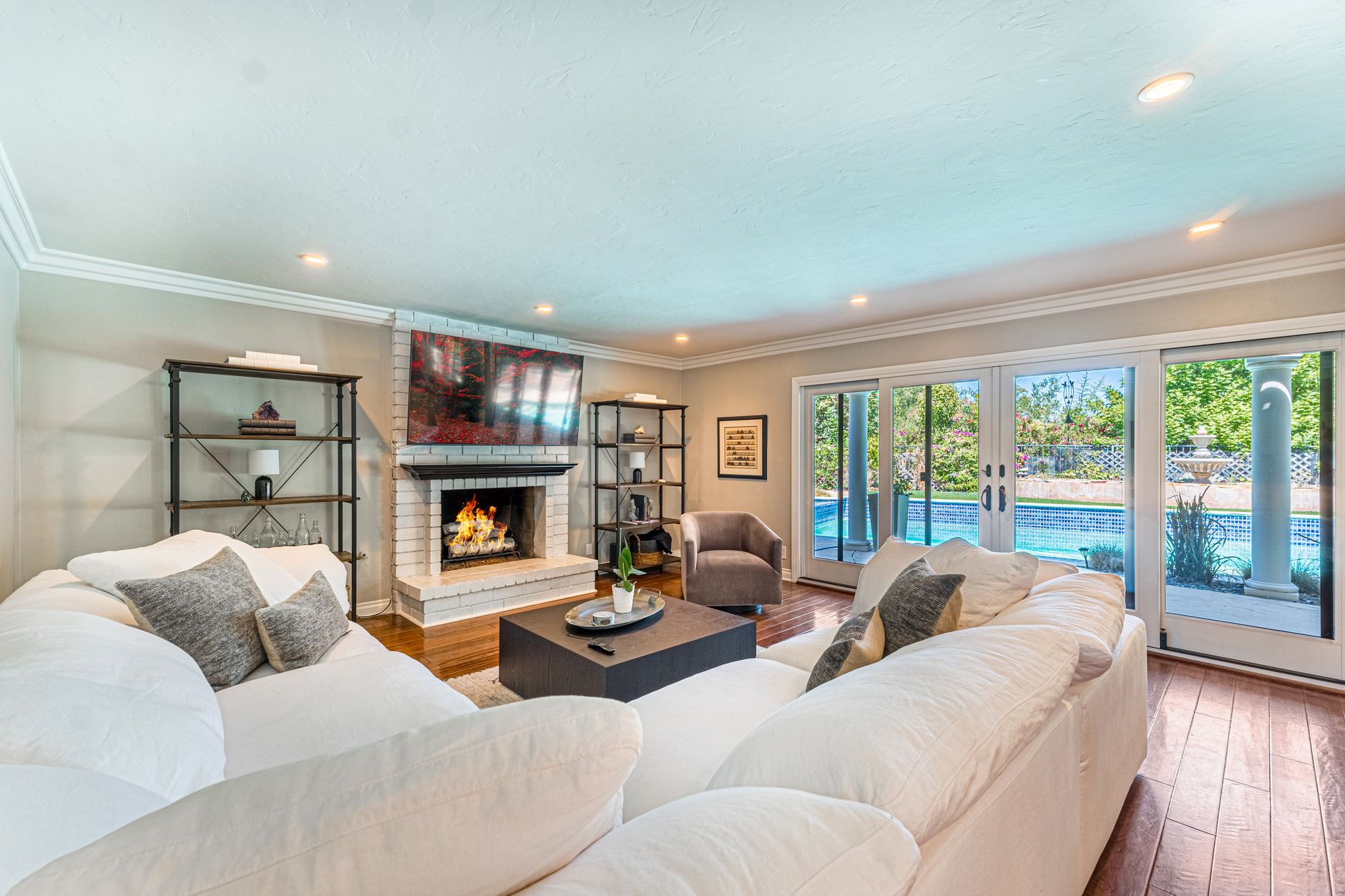 A spacious and modern living room with fireplace, pool view, and elegant decor.