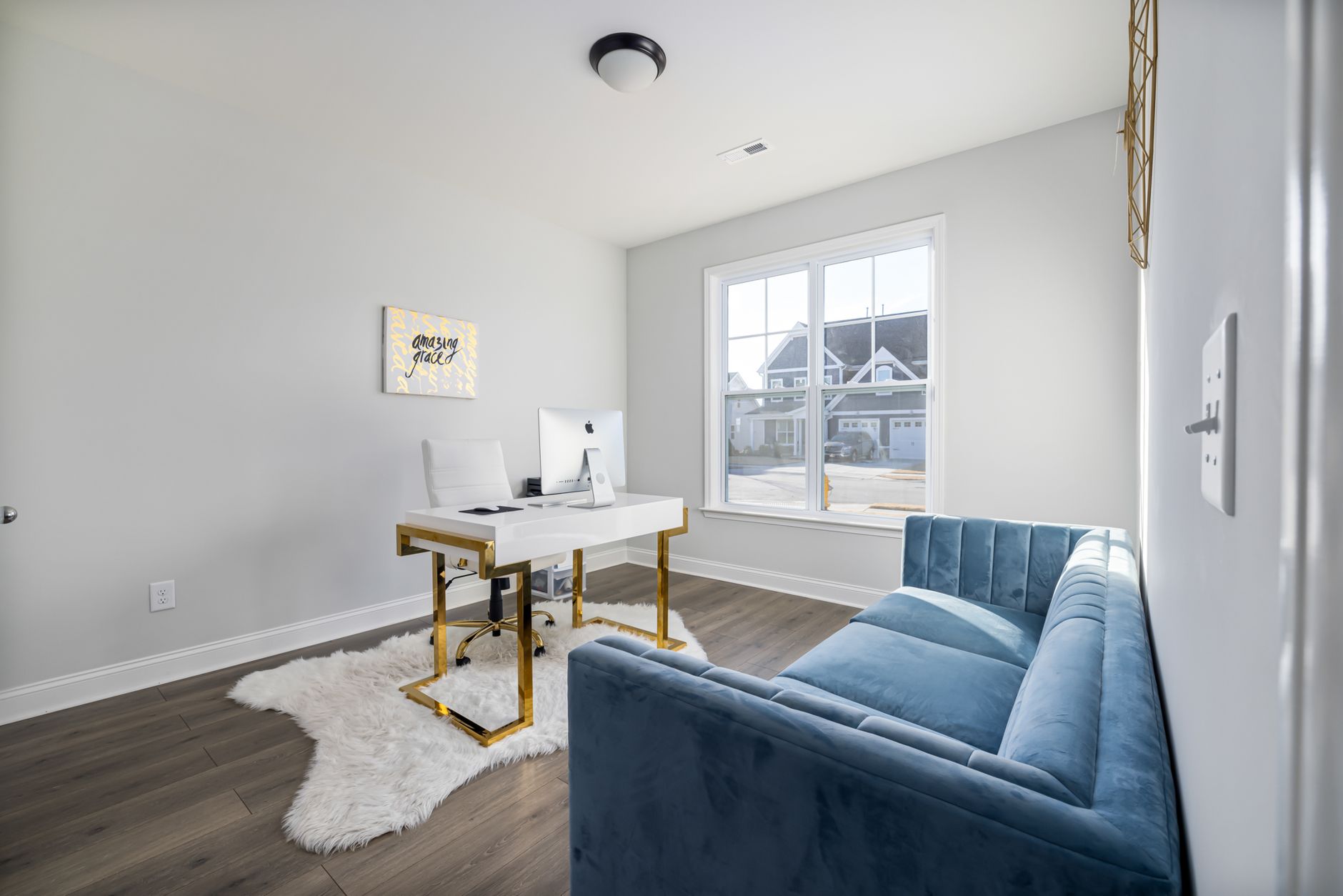 A stylish modern home office featuring a velvet couch and sleek desk with natural light.