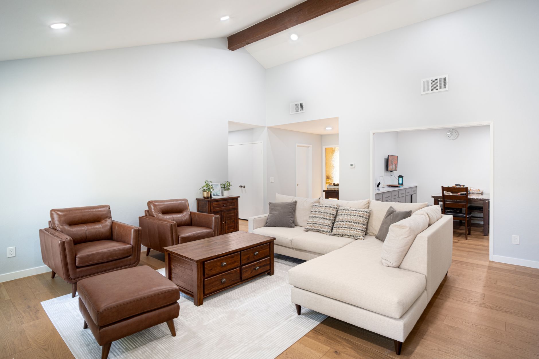 Spacious living room with leather chairs, wooden furniture, and a white sectional sofa.
