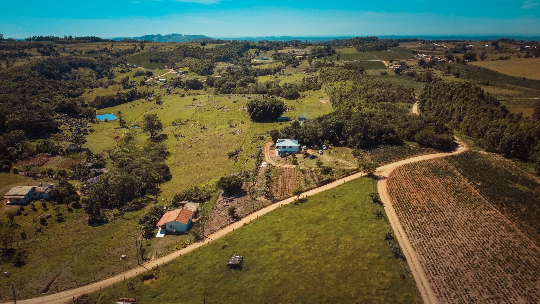 Scenic aerial view of rolling rural landscape in Tubarão, Brazil with croplands and houses.