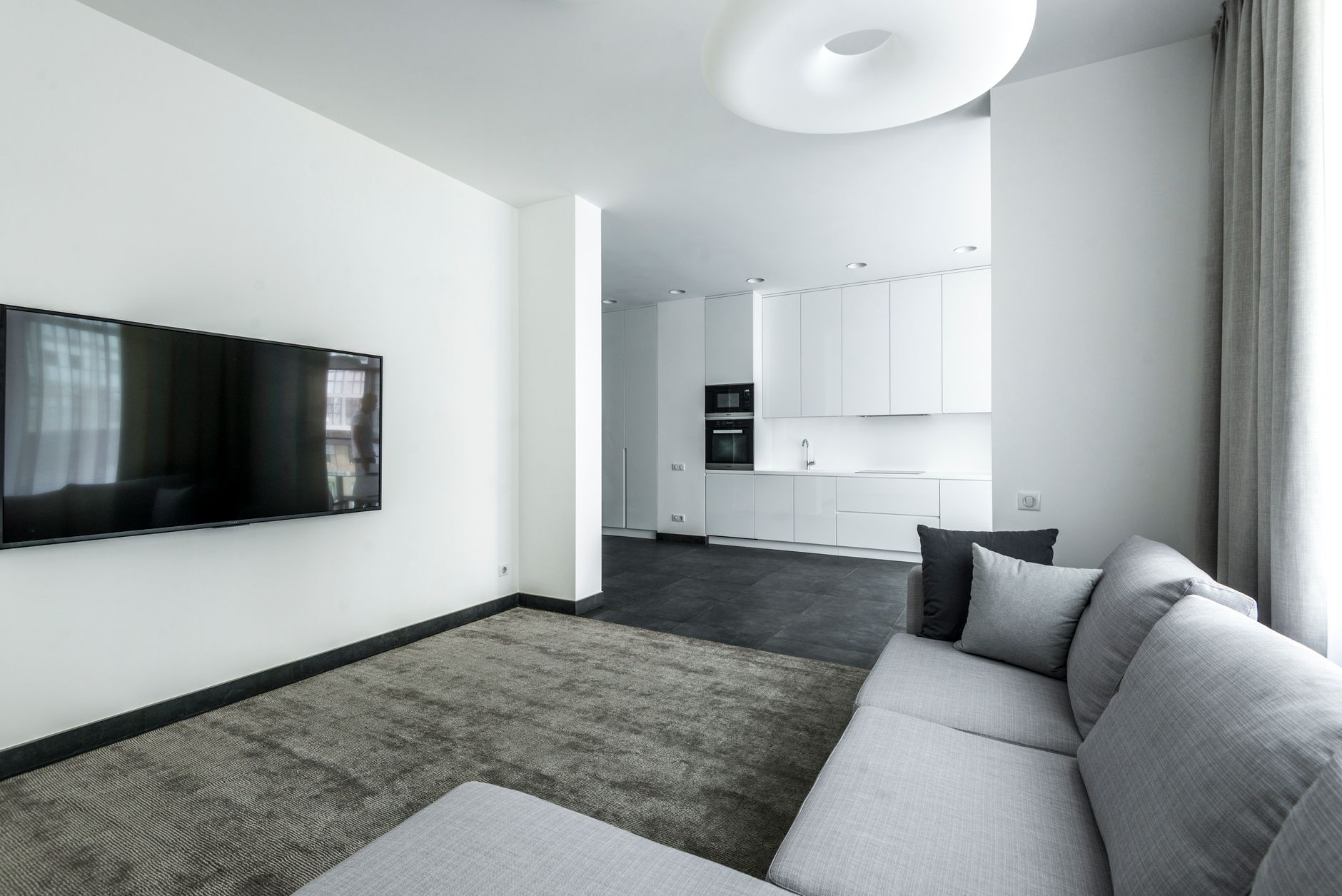 Bright and spacious minimalist living room with an open kitchen layout, modern furniture and decor.