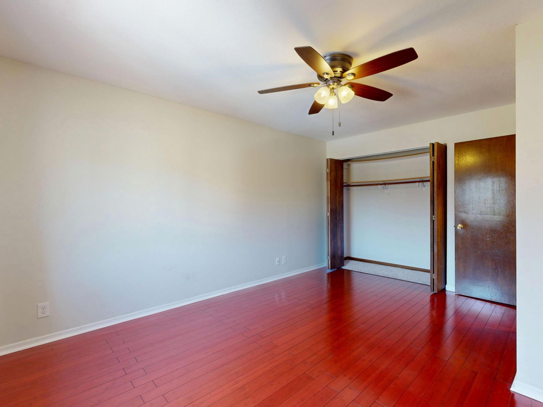 Modern empty room with hardwood floors and ceiling fan, ready for furnishing.