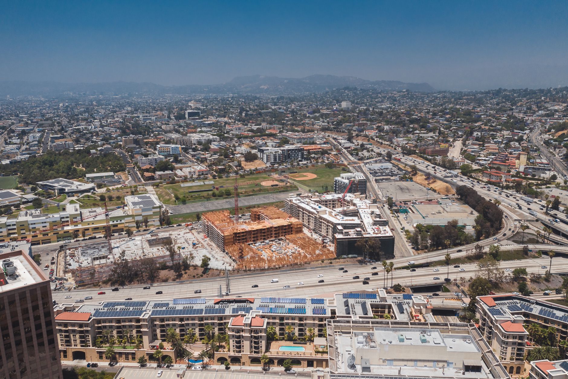 Aerial view showcasing the urban sprawl of Los Angeles with construction sites and highways visible.