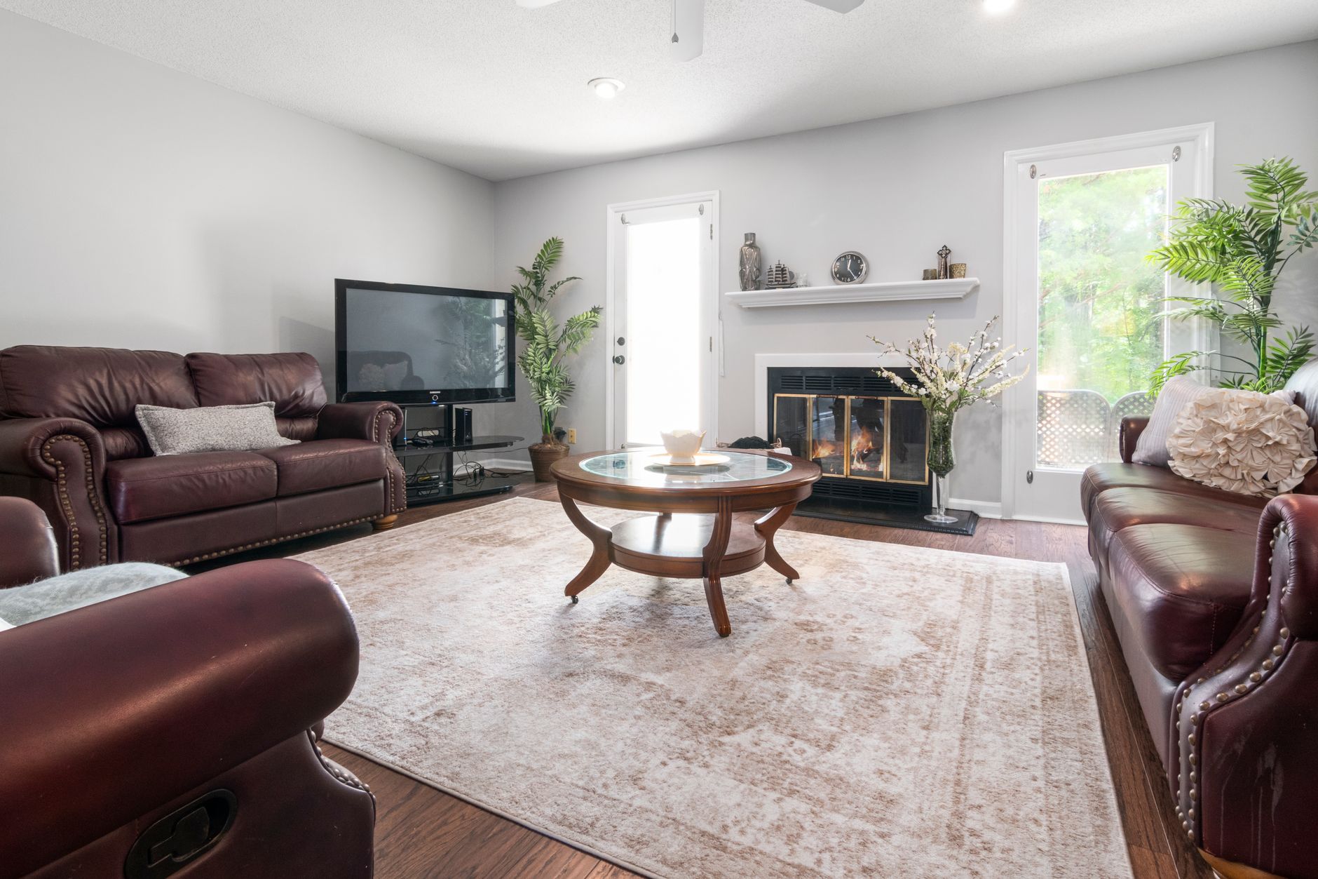 Luxurious living room featuring leather sofas, fireplace, and large windows.