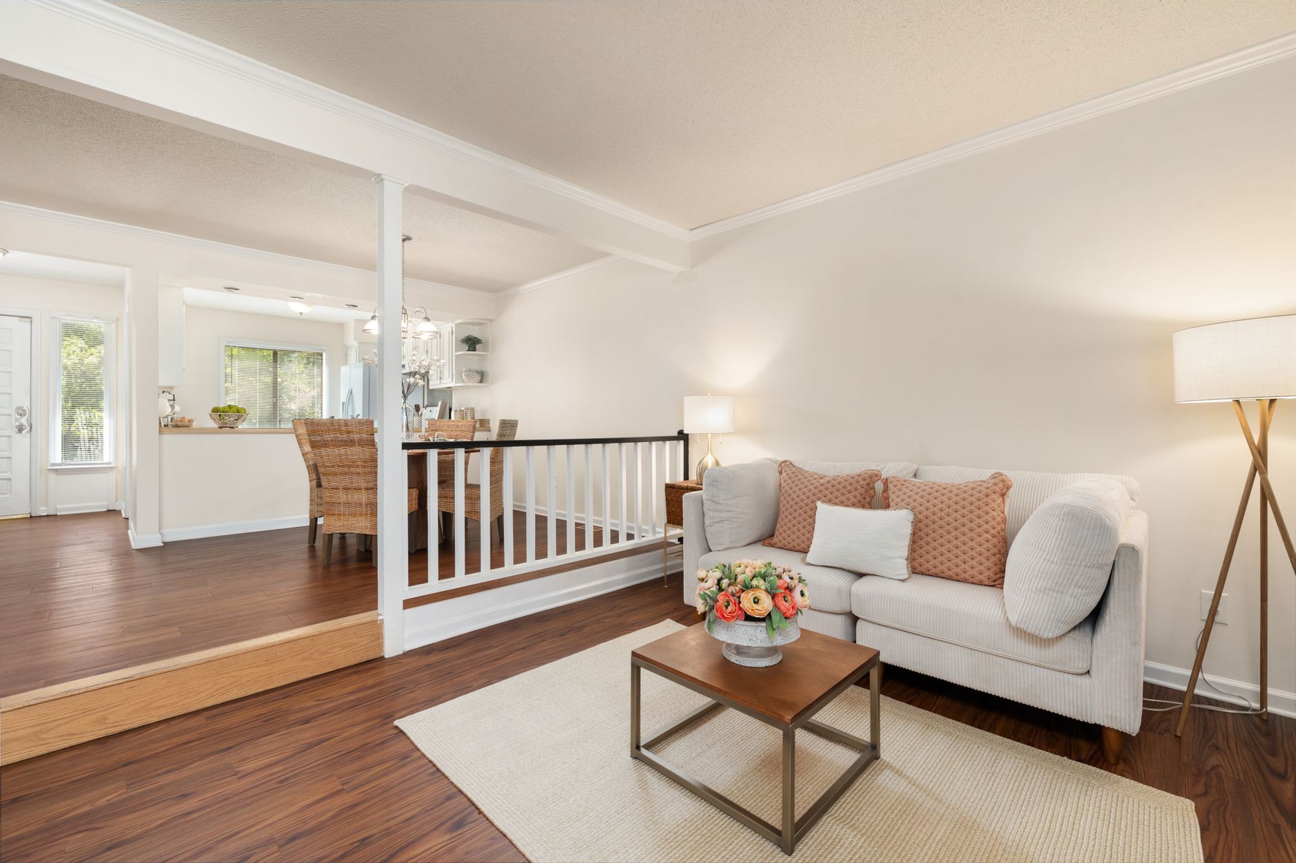 Modern living room with white sofa, chic decor, and dining area in a bright, open space.