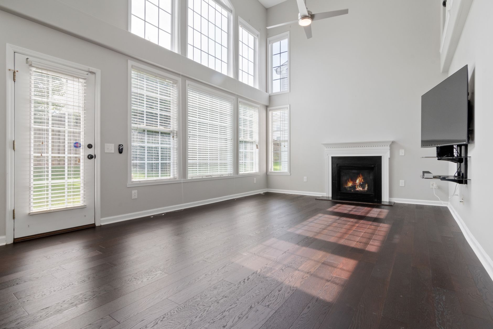 Spacious unfurnished living room featuring large windows and a cozy fireplace.