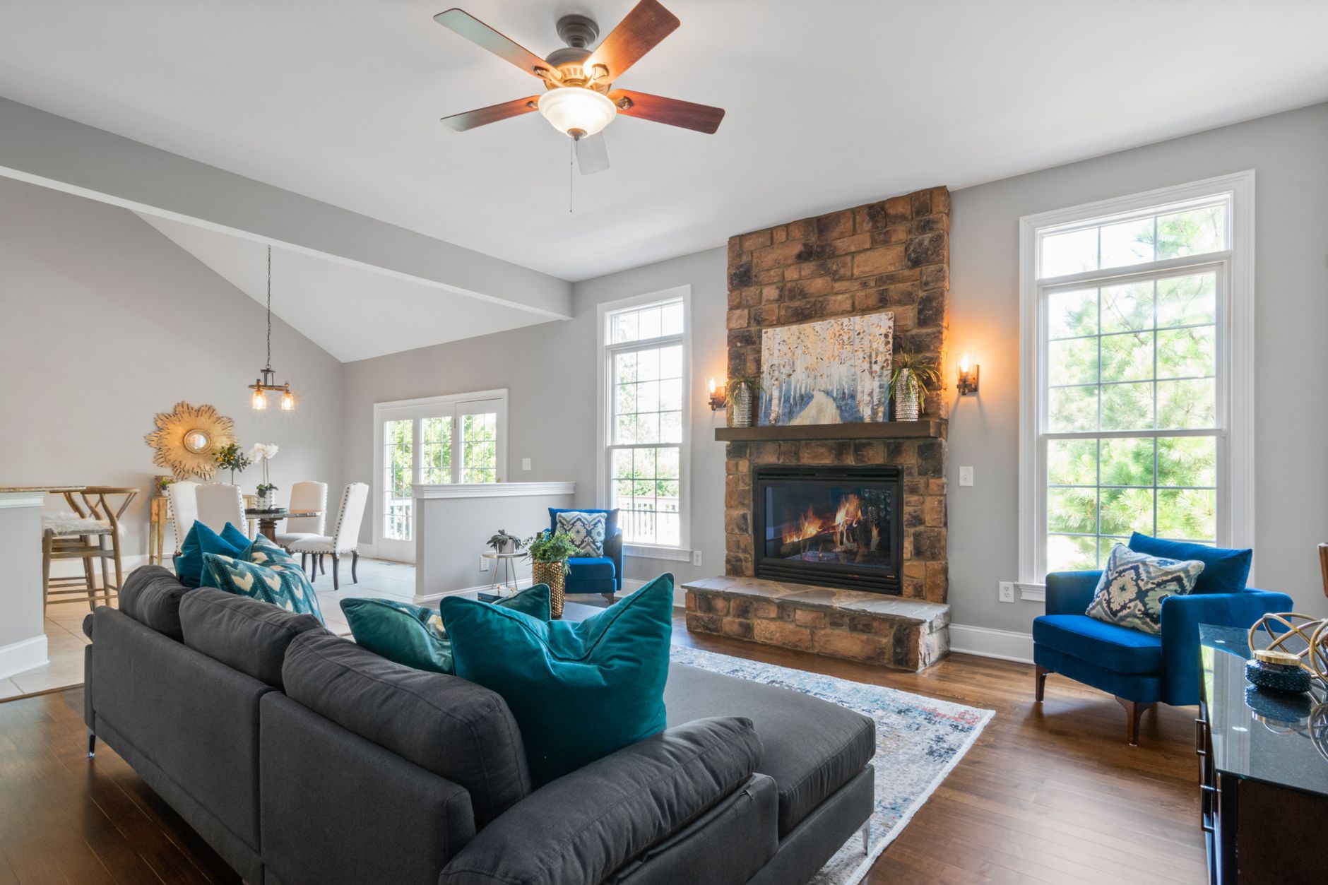 Stylish living room featuring a stone fireplace, modern furniture, and natural lighting.