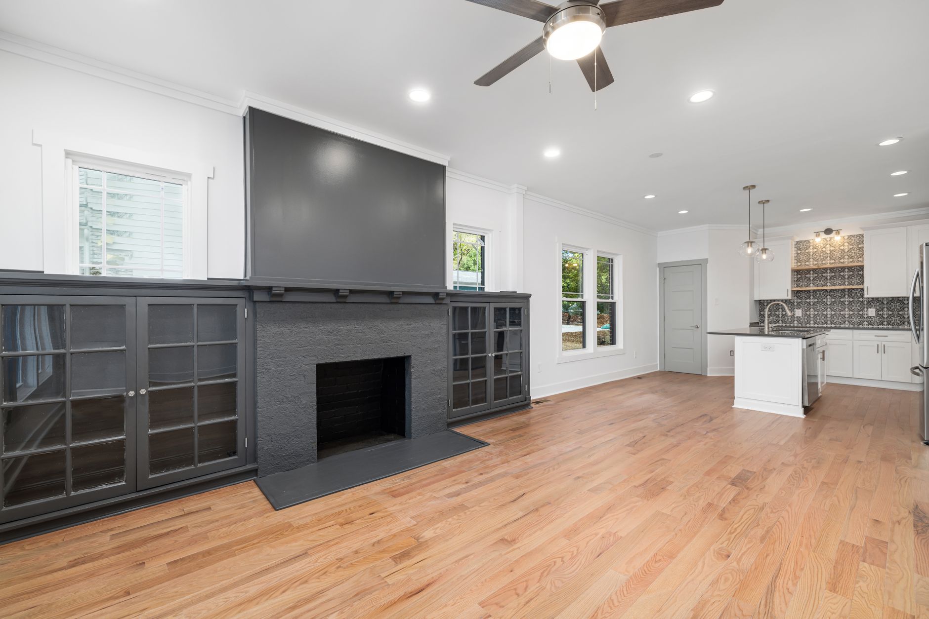 Spacious modern living room with fireplace and sleek kitchen design.
