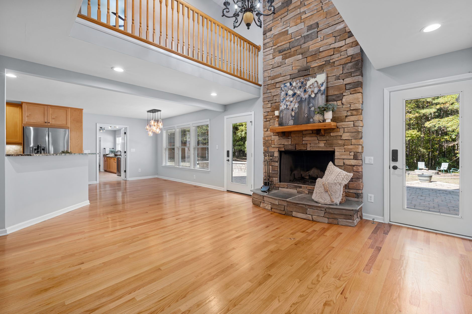 Bright and spacious living room showcasing a modern stone fireplace and high ceilings.