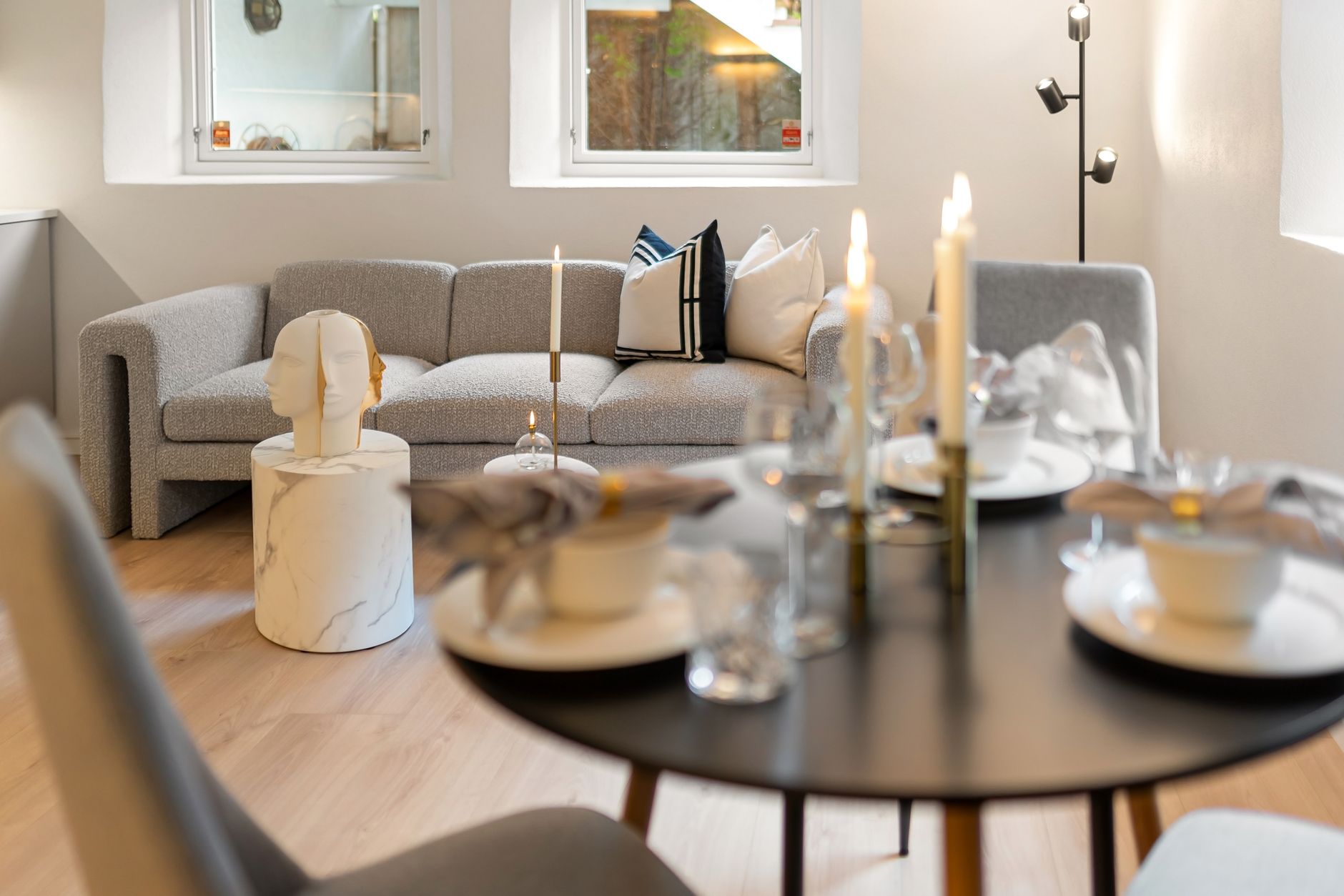 A modern living room featuring a gray sofa, decorative candles, and an elegant table setup with selective focus.