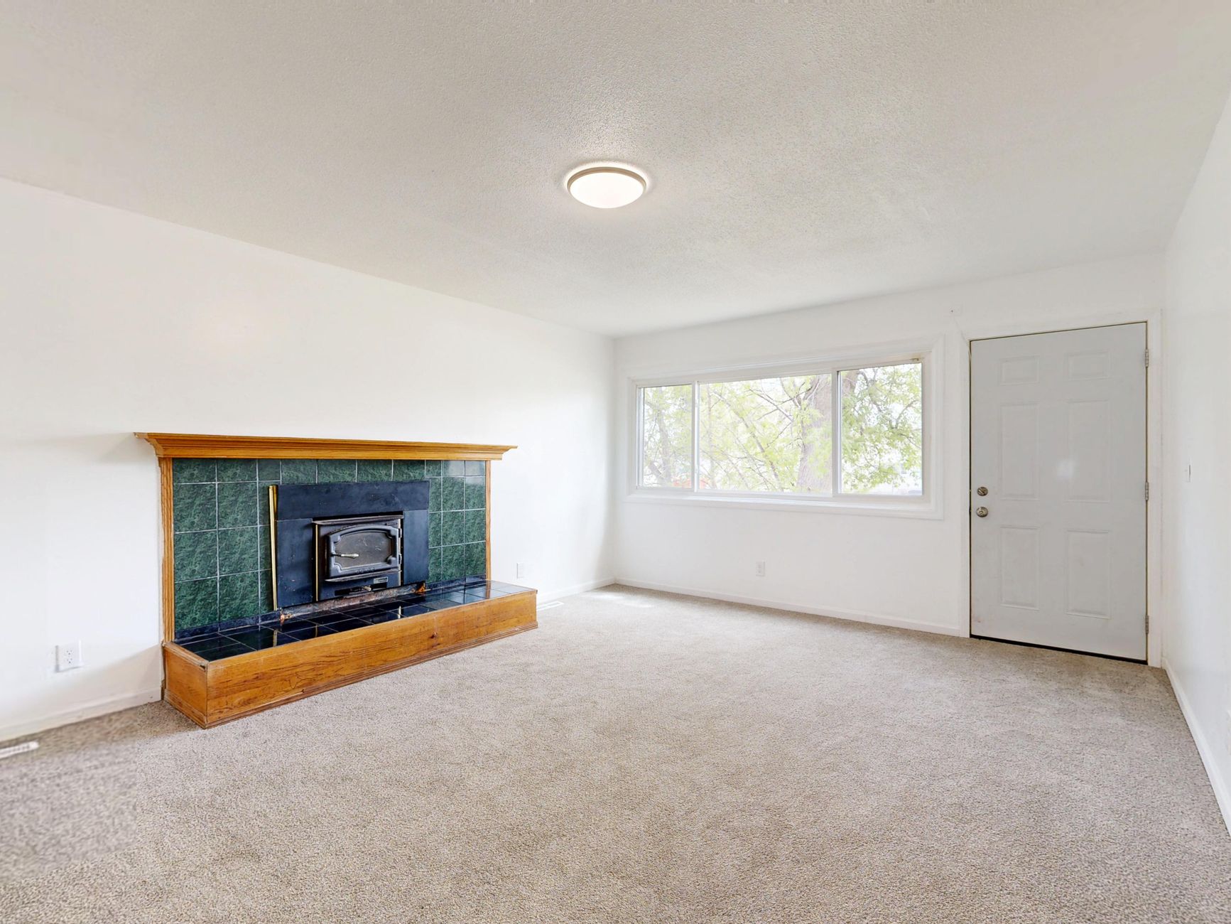 Bright empty living room featuring a modern fireplace and large window view.