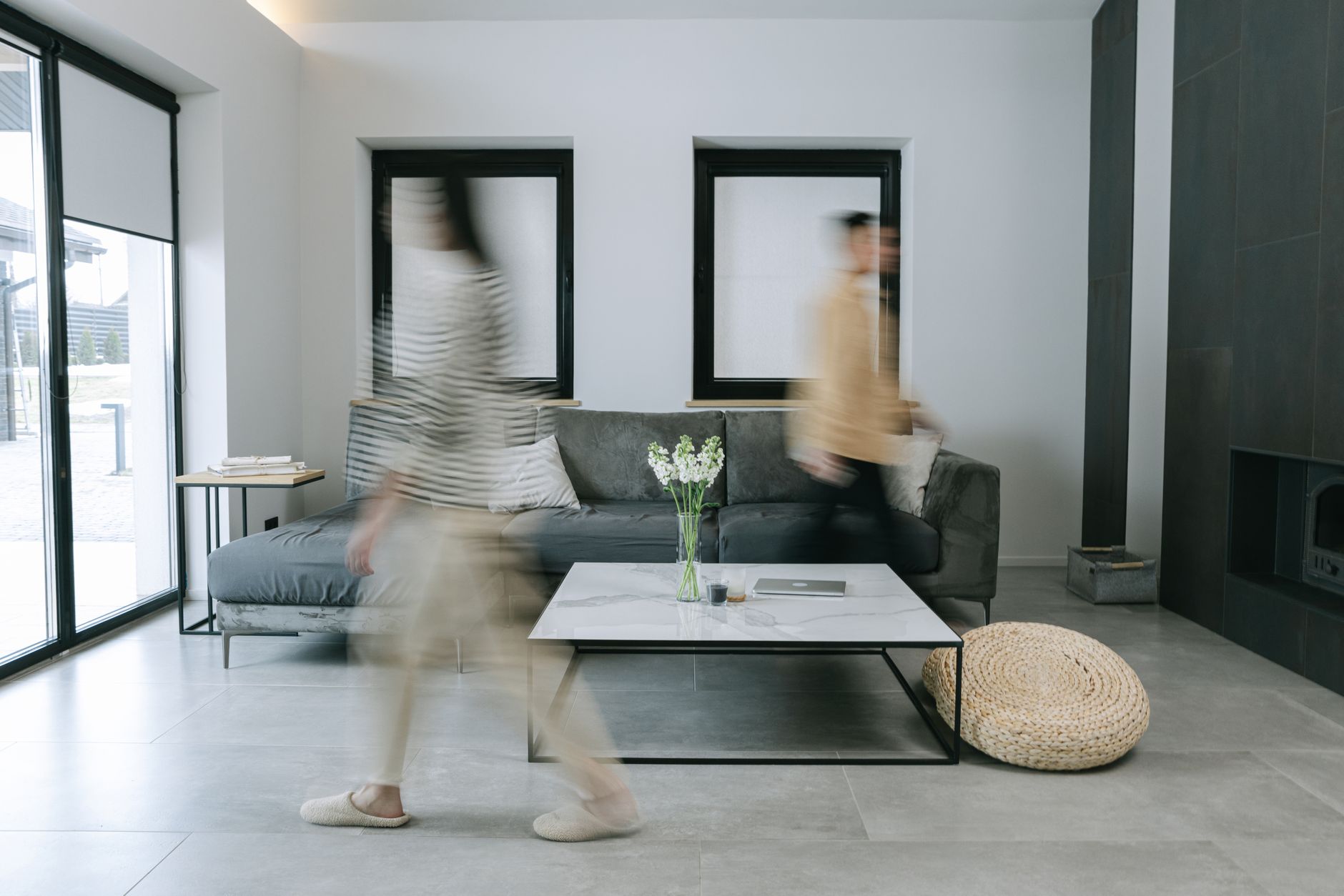 A stylish living room with minimalist decor featuring people in motion blur, creating dynamic energy.