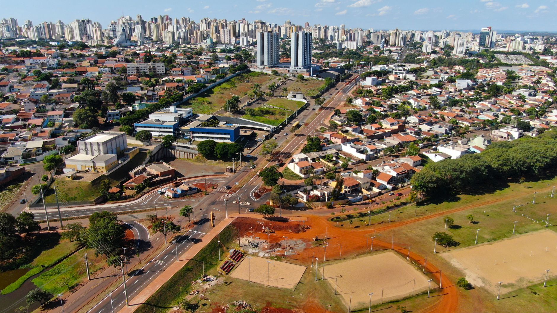 Drone shot of Londrina, Brazil showcasing urban architecture, roads, and greenery under a clear blue sky.