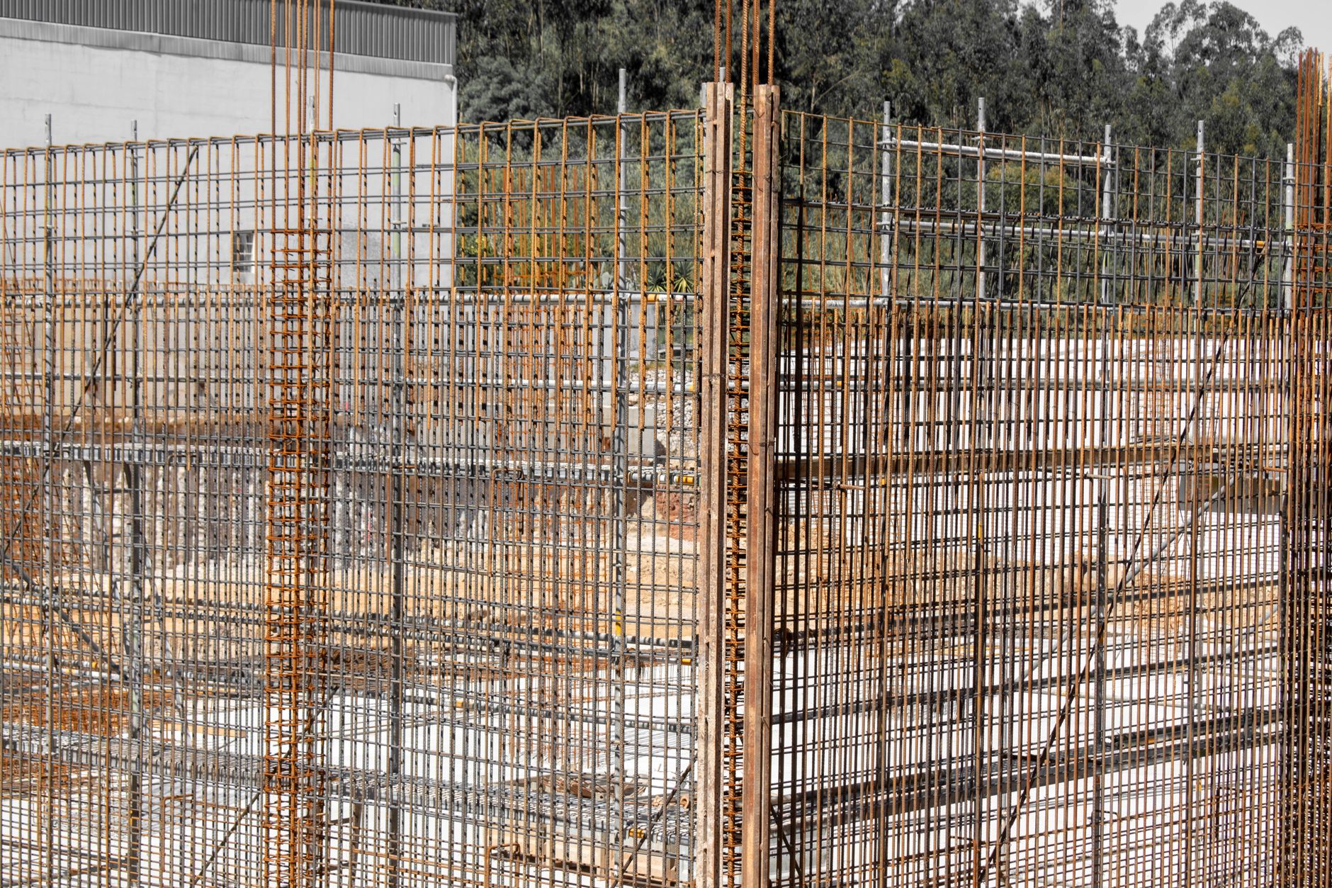 Close-up view of rusting reinforcement steel bars at a construction site with surrounding wooden formwork.