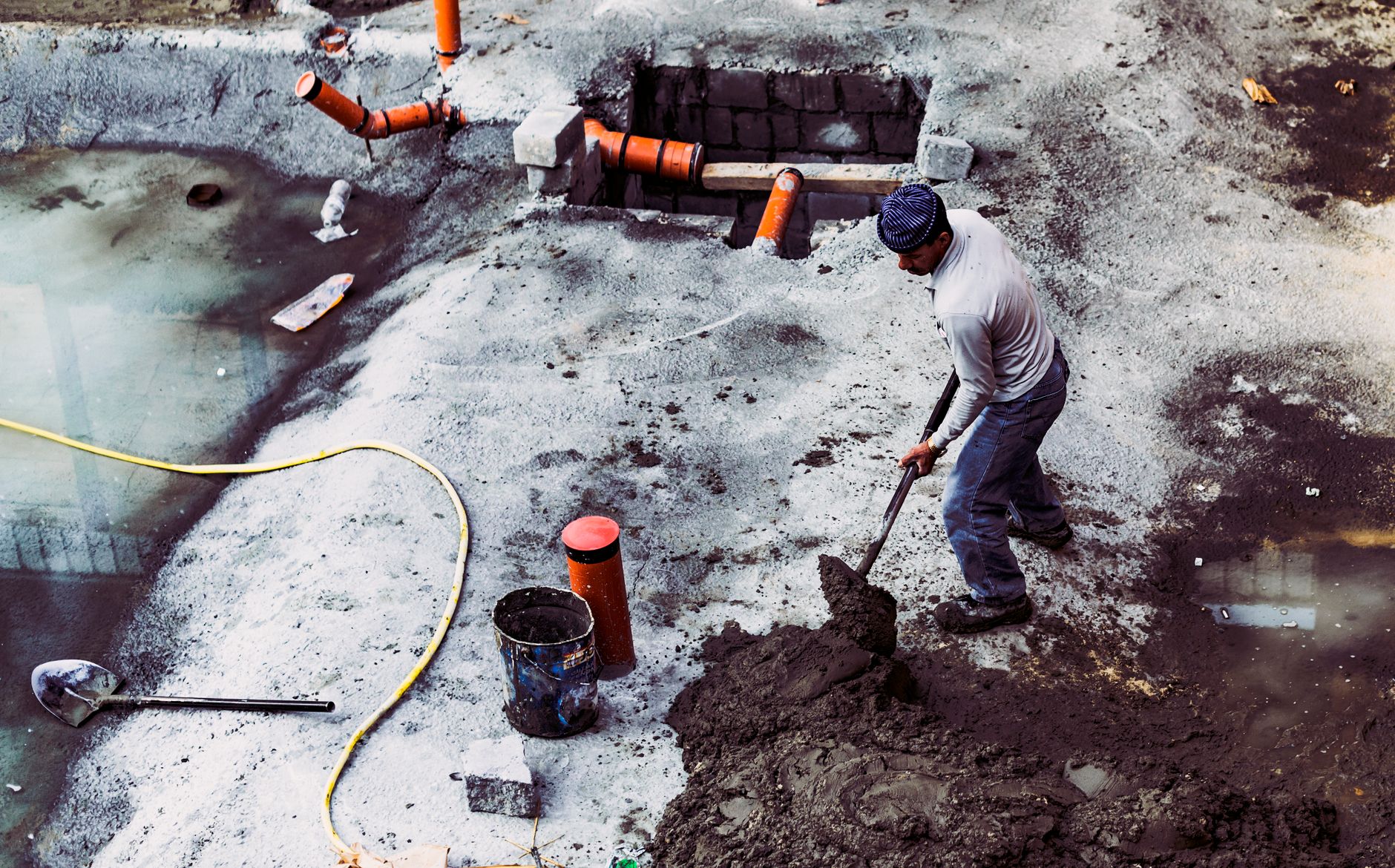 A male construction worker shoveling soil at an outdoor building site in Dubai, UAE.