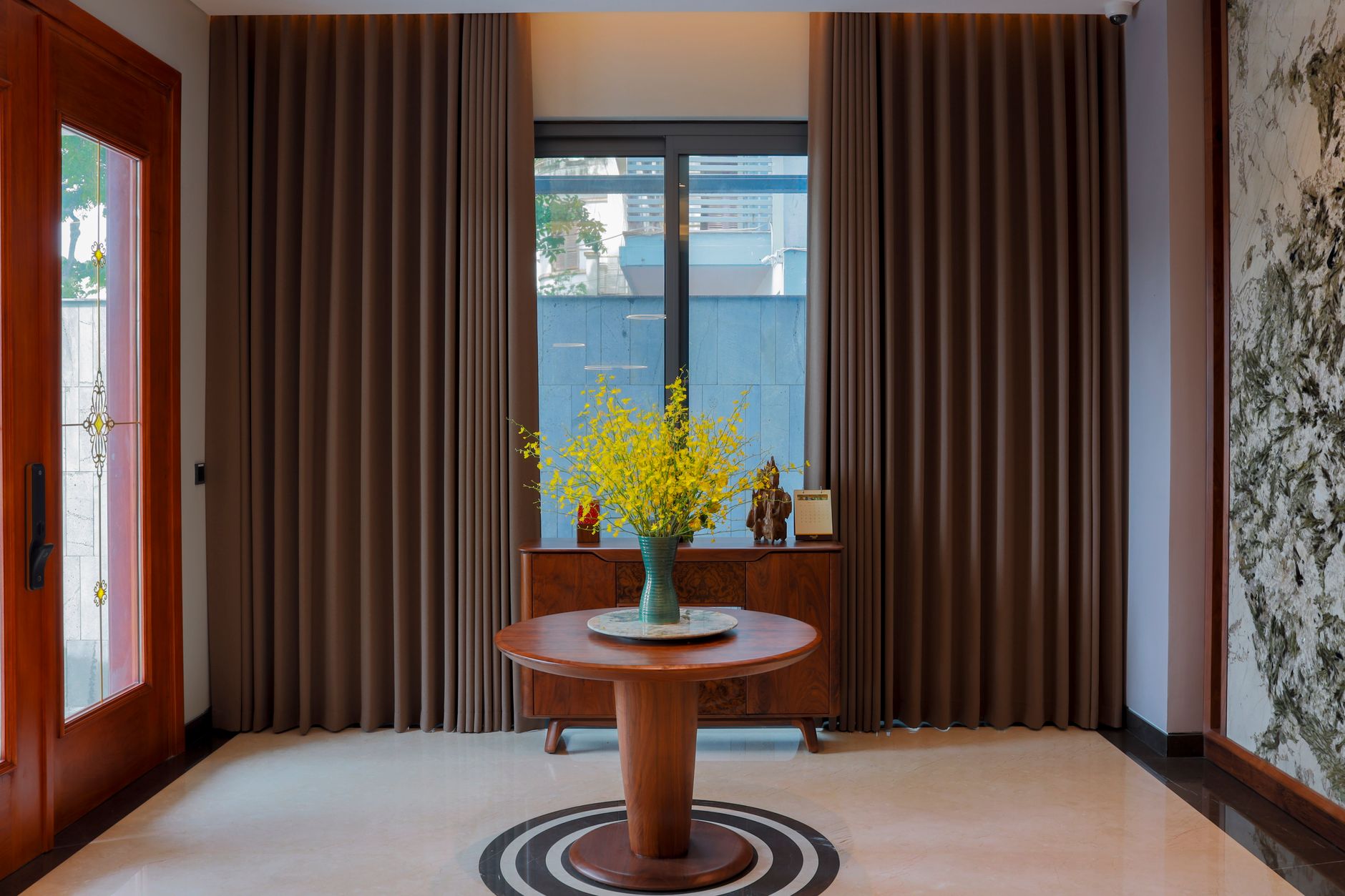 A modern indoor setting featuring a round table with a vibrant yellow flower arrangement.
