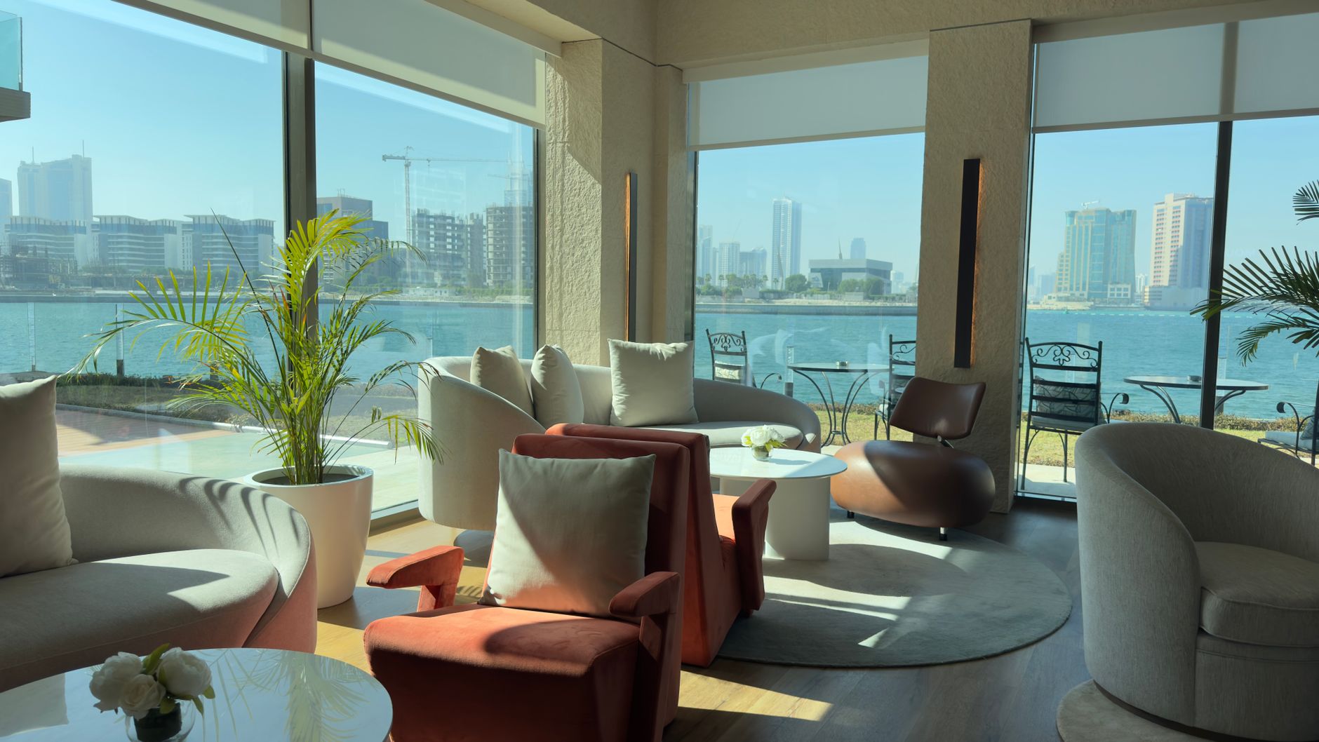 Spacious waterfront lounge featuring modern decor and scenic city skyline views through large windows.
