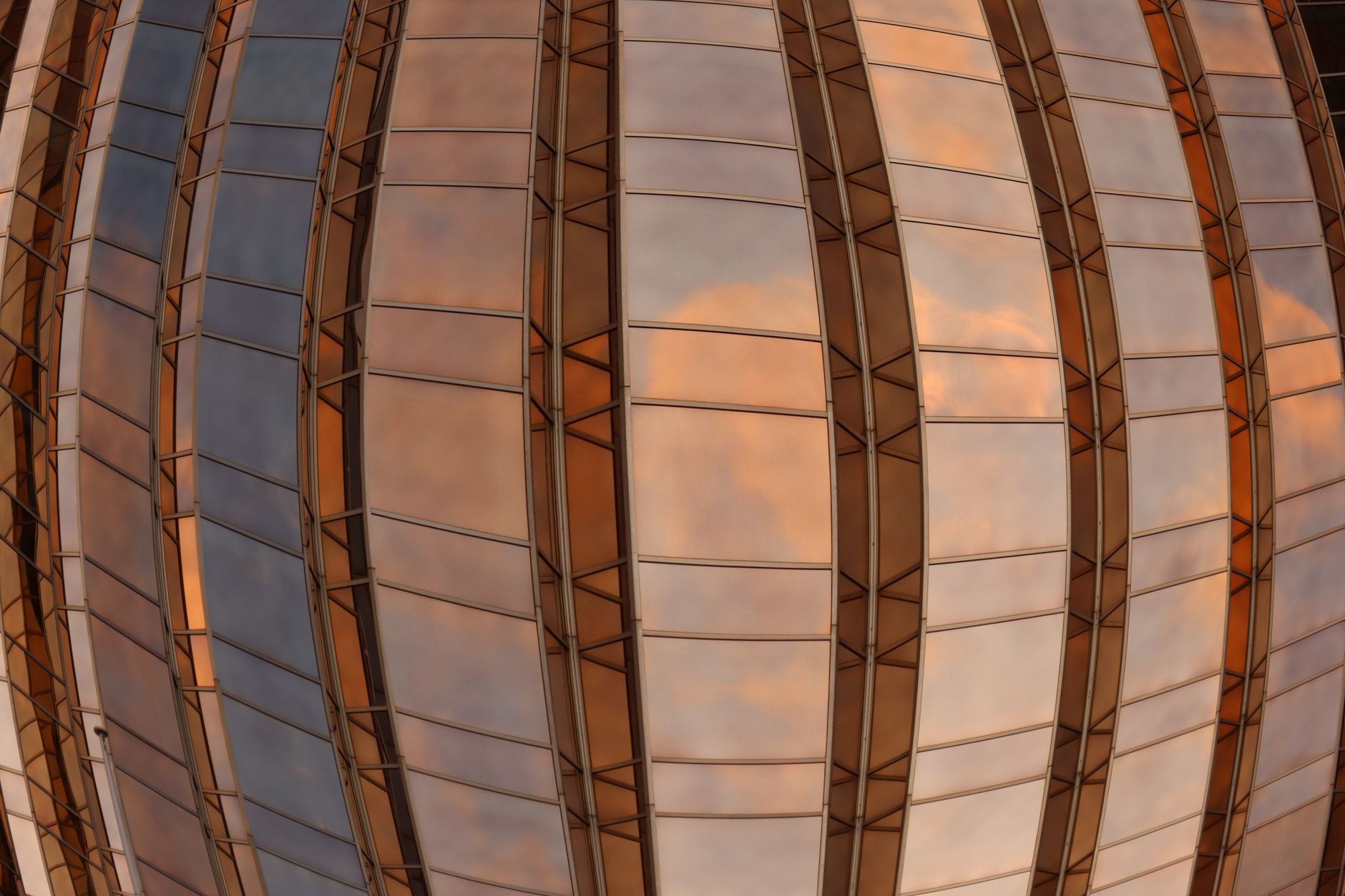 Futuristic glass dome in Melbourne reflecting a colorful sky.