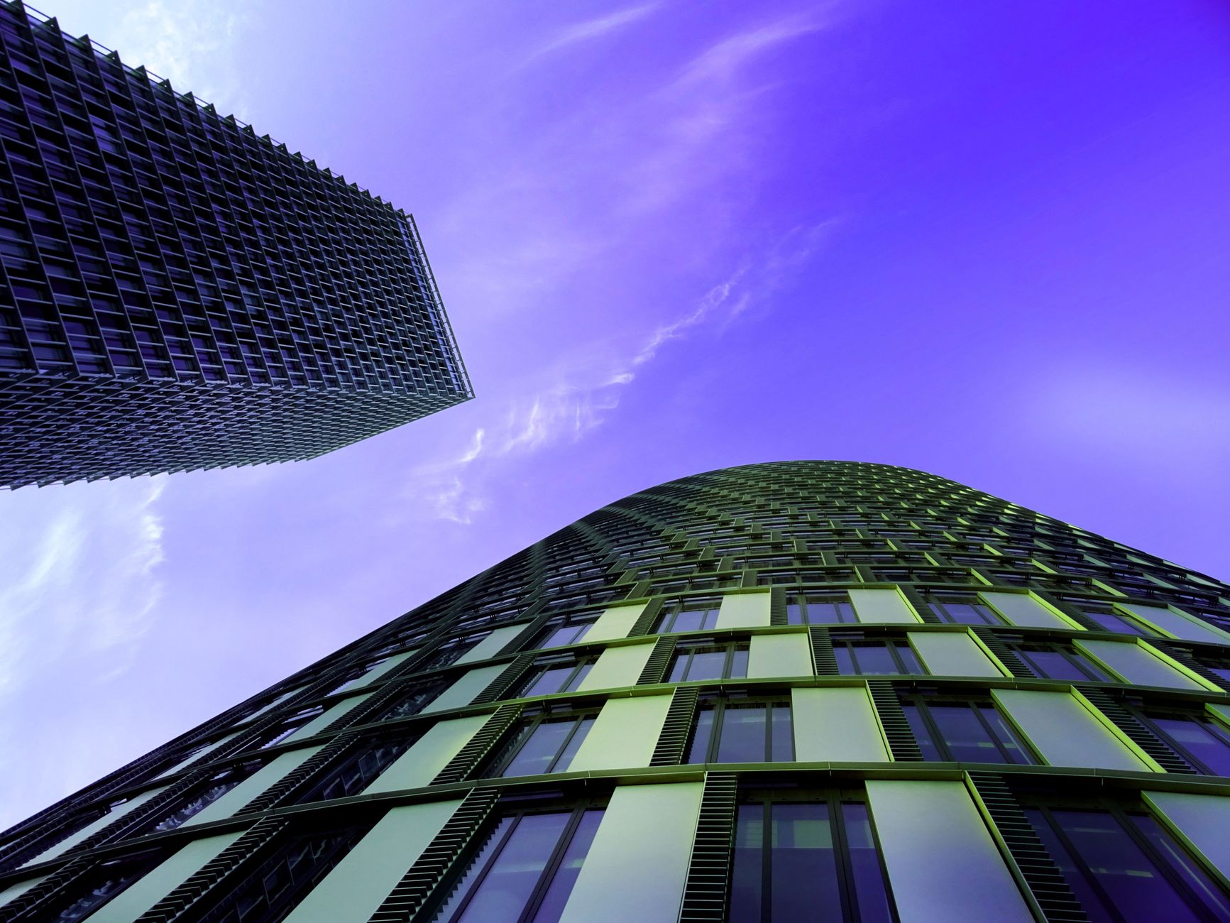 Dramatic perspective of futuristic skyscrapers against a vibrant blue sky.