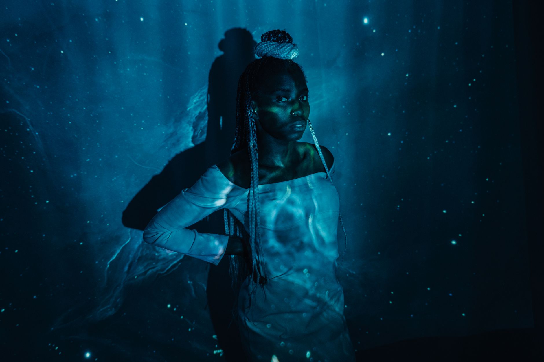 Creative portrait of a woman with cosmic light projections creating an ethereal and mysterious atmosphere.