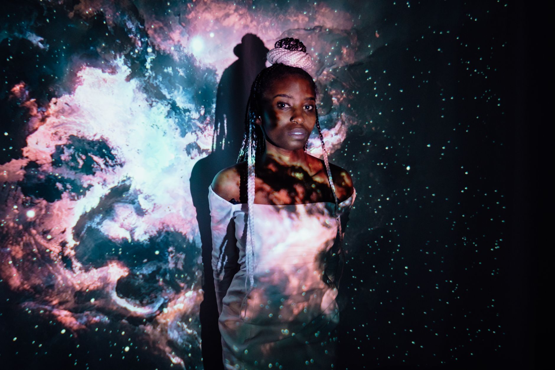 Captivating portrait of an African woman with a galaxy projection creating a surreal atmosphere.