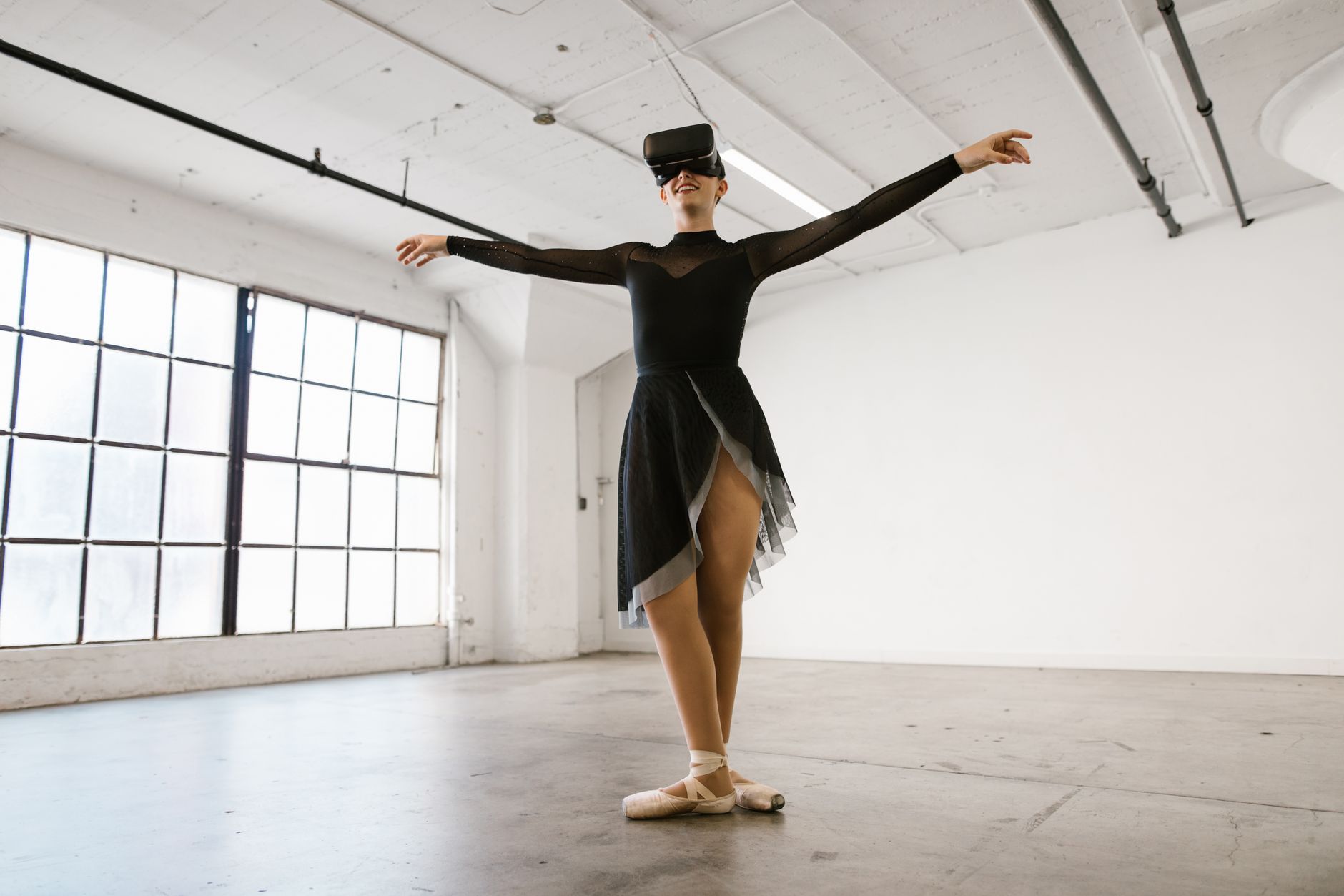 A ballet dancer wearing VR goggles performs gracefully indoors, combining technology and art.