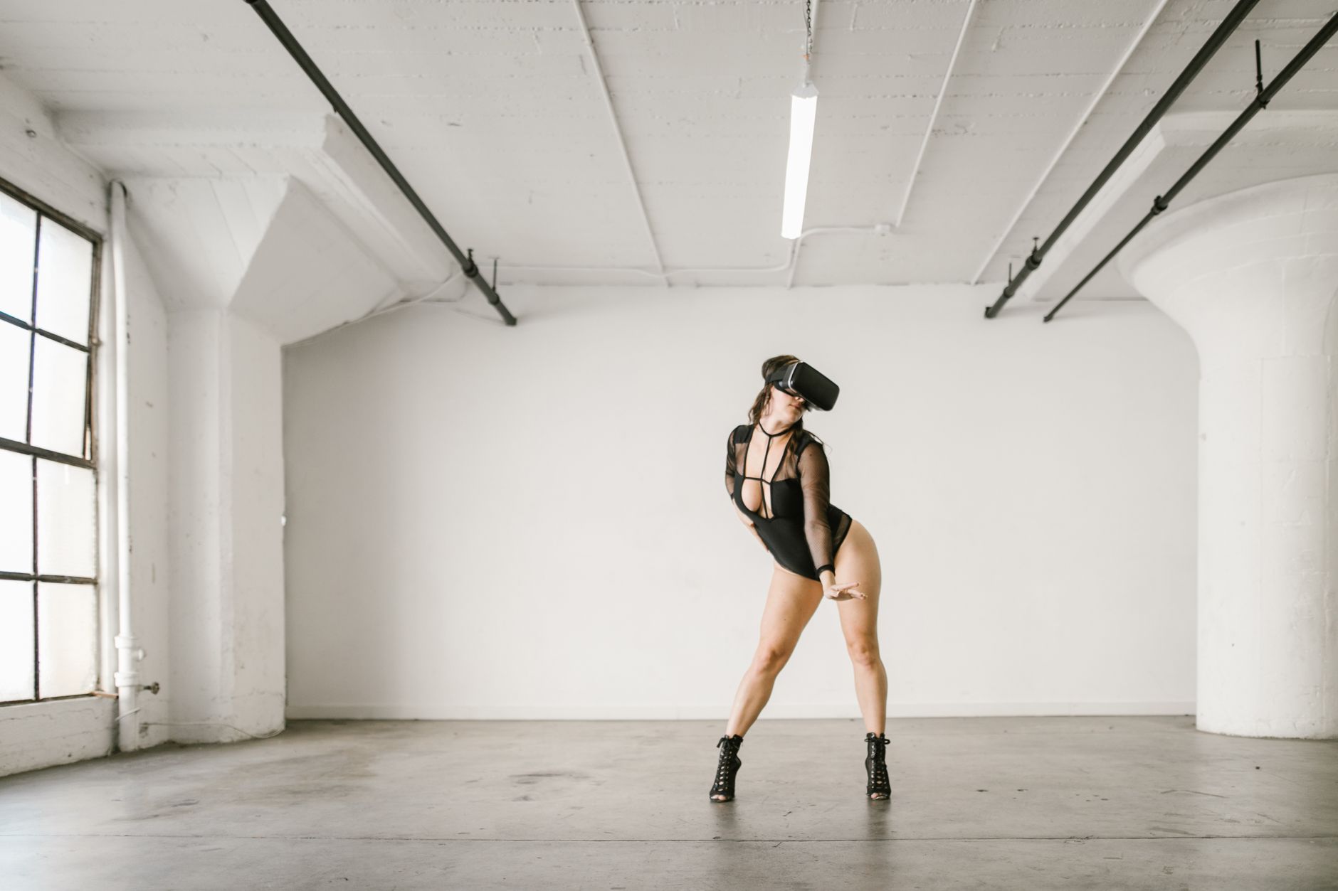 A woman in VR headset dancing stylishly indoors, showcasing modern technology and fashion.