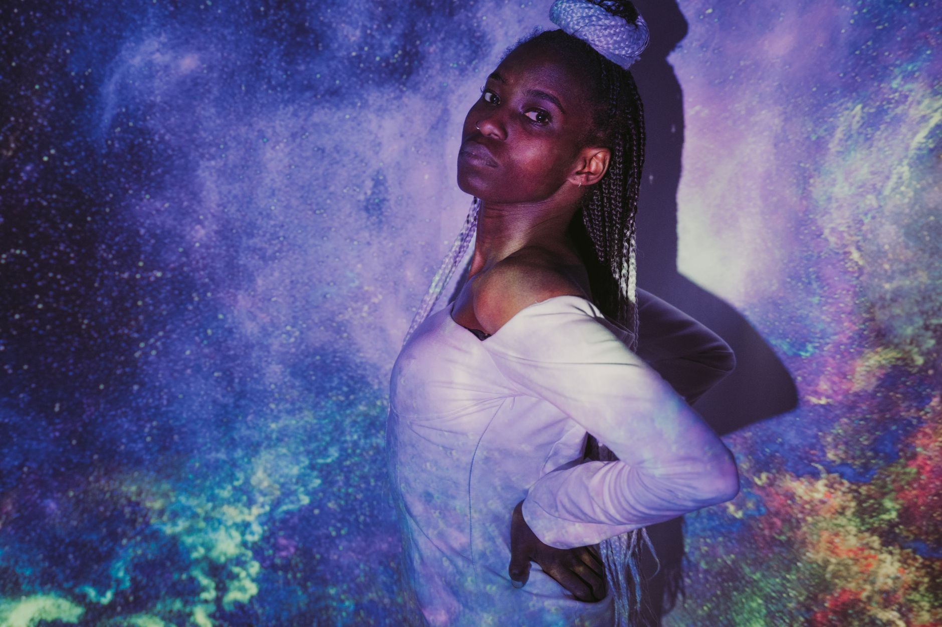 A woman posing with galaxy projections creating a cosmic and artistic vibe.